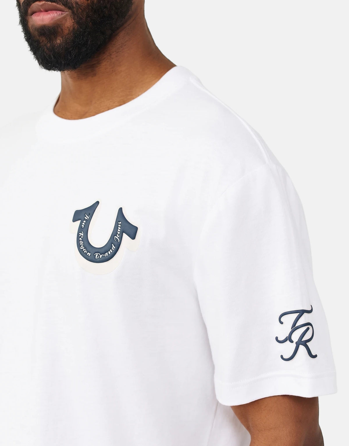Close-up of a man wearing a white True Religion Super True T-Shirt with the brand's logo visible on the chest.