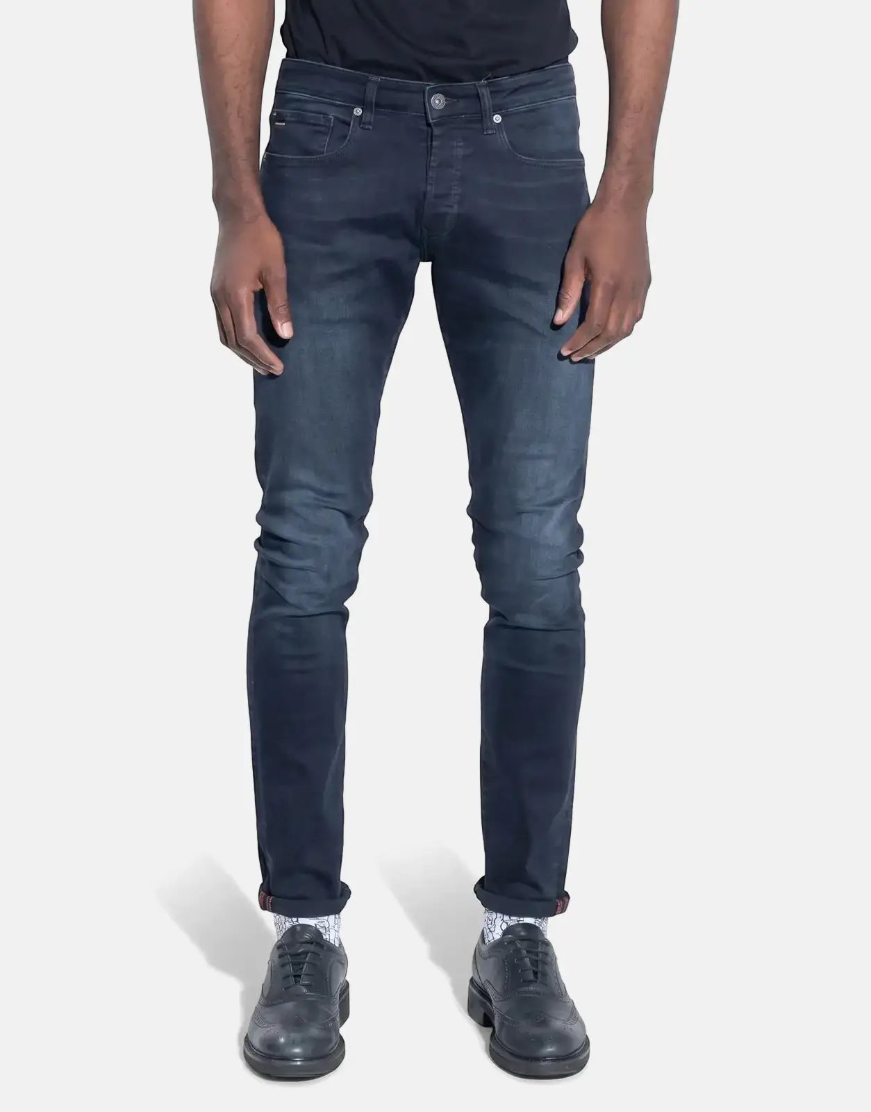 TSHEPO Takalani Jeans, dark blue, slim-fit, worn by a person, paired with patterned socks and black leather shoes.