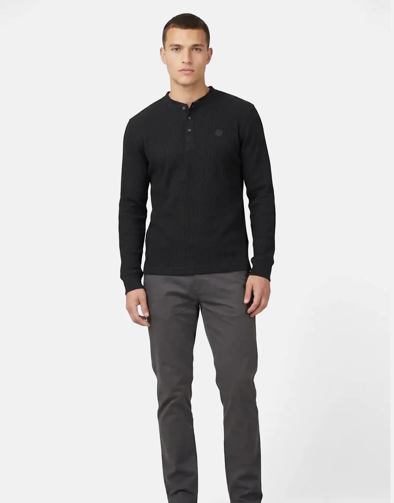 Male model wearing a black Ben Sherman Henley waffle knit long-sleeve top and grey pants, full body shot.