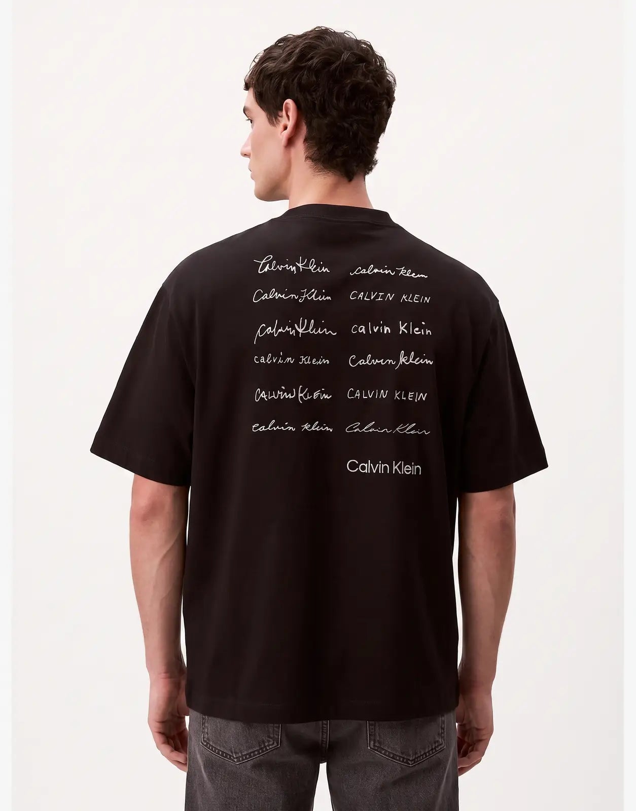Calvin Klein 16s April Graphic Seasonal Fashion black t-shirt, viewed from the back, featuring multiple white 'Calvin Klein'