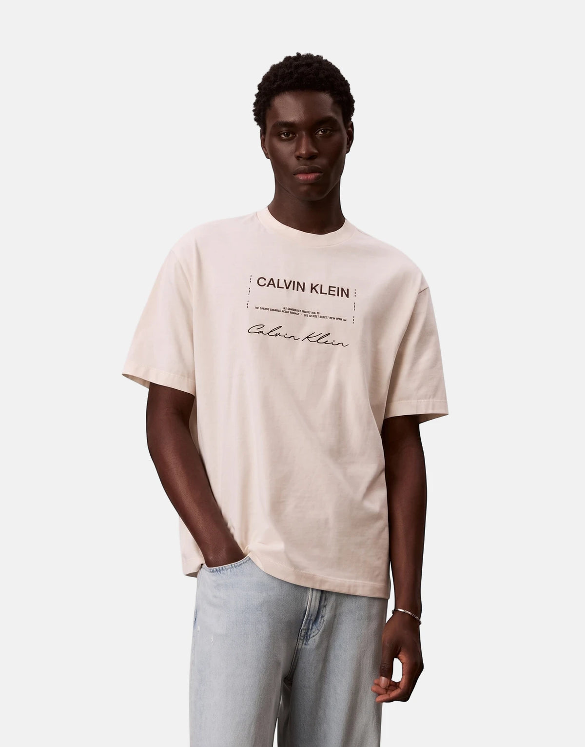Male model wears a Calvin Klein 16s April Graphic Seasonal Fashion white t-shirt with light blue jeans.