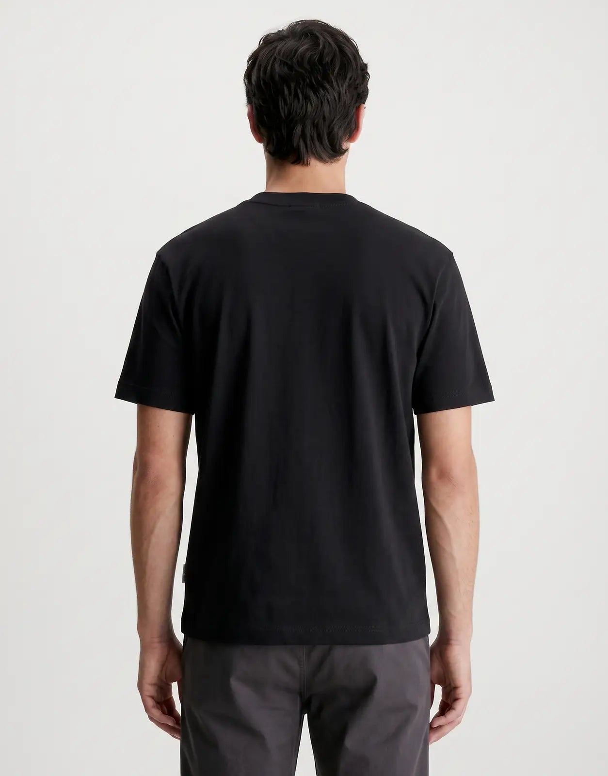 Rear view of the Calvin Klein 16s Tricolor Monologo Graphic Black T-Shirt, showcasing its smooth fabric and short sleeves.