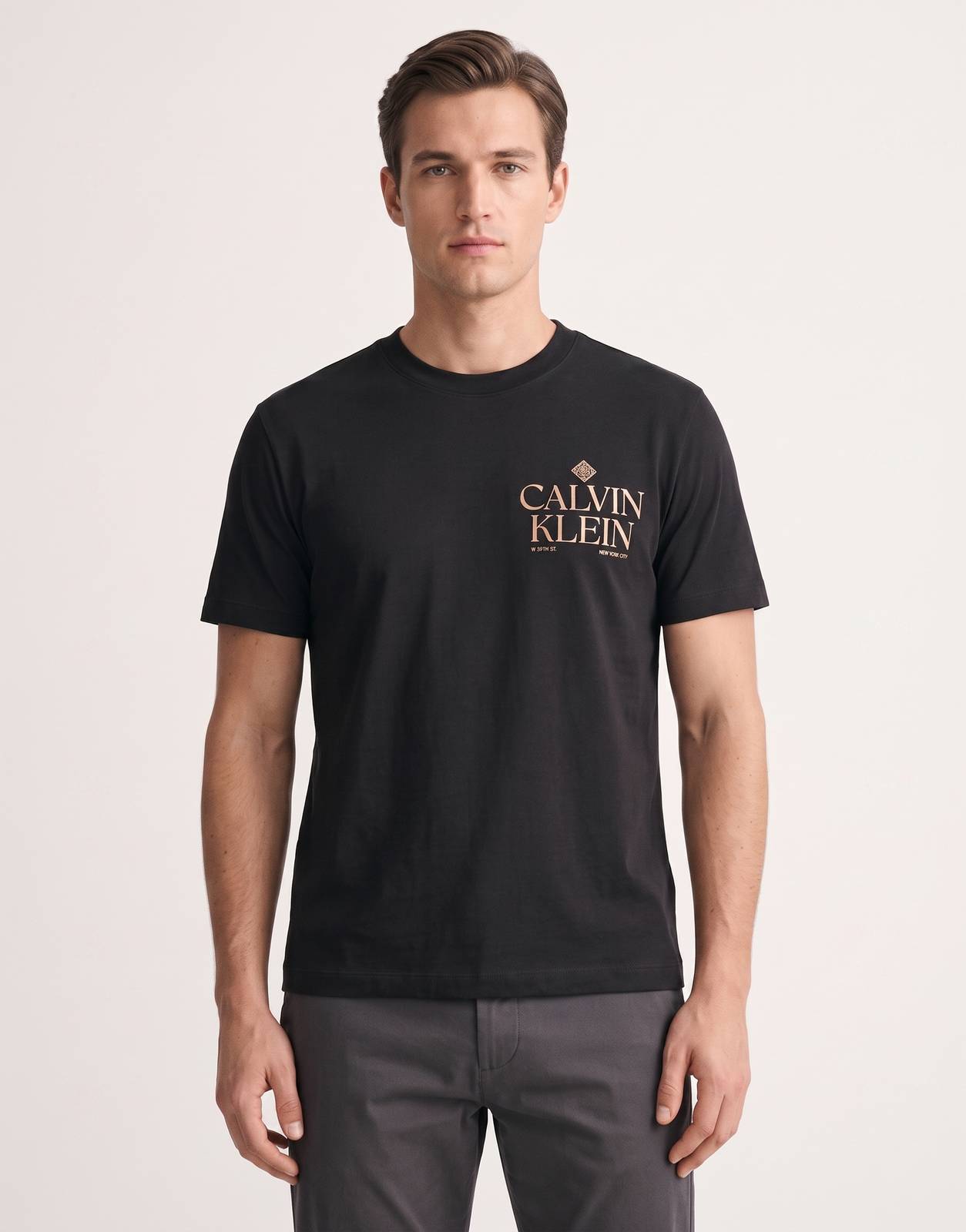 A man models a black Calvin Klein 20s Roses graphic short-sleeve t-shirt from the front, in a studio setting.