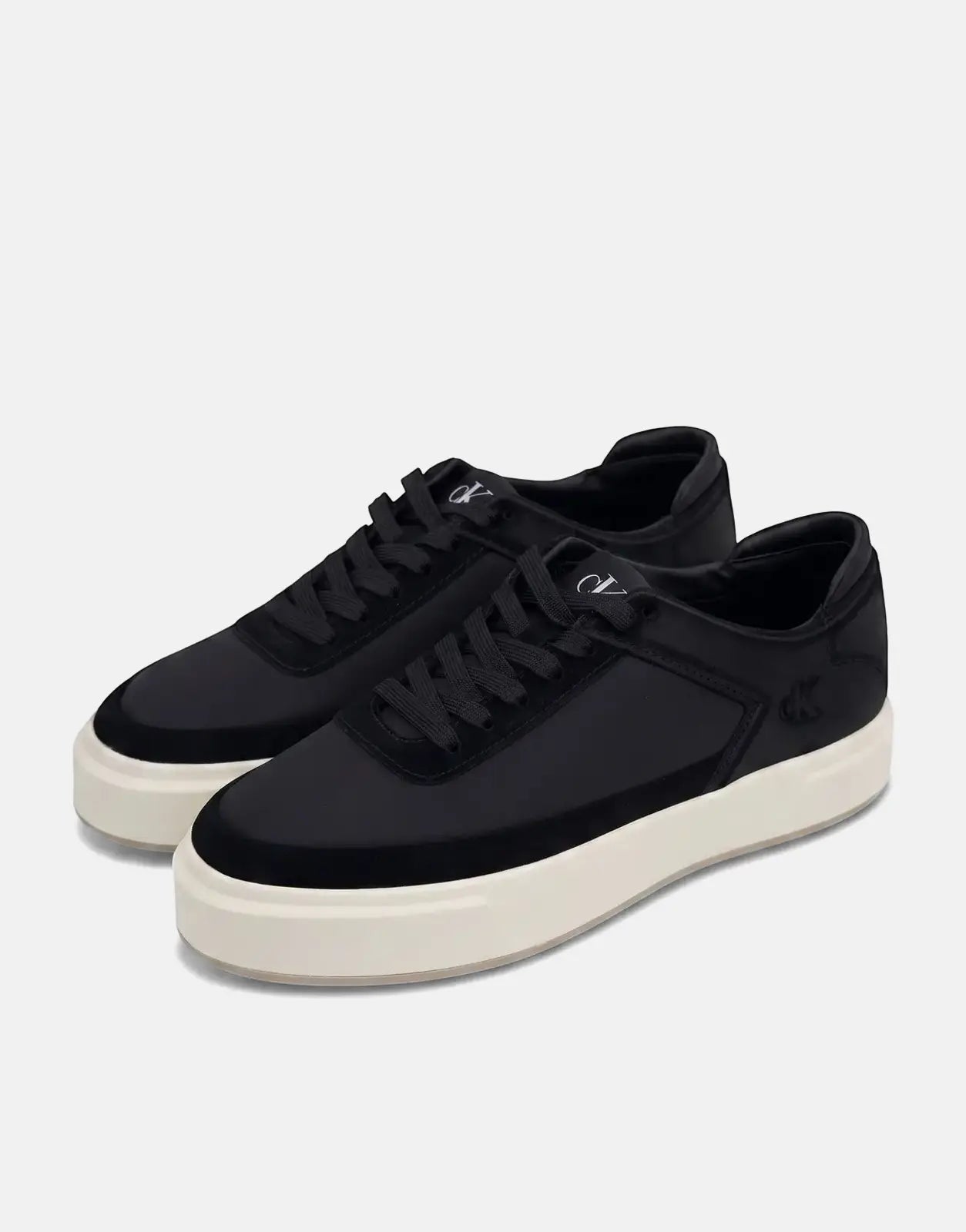 A pair of black Calvin Klein Basket Cupsole lace-up sneakers with chunky off-white soles, shown from a slightly elevated