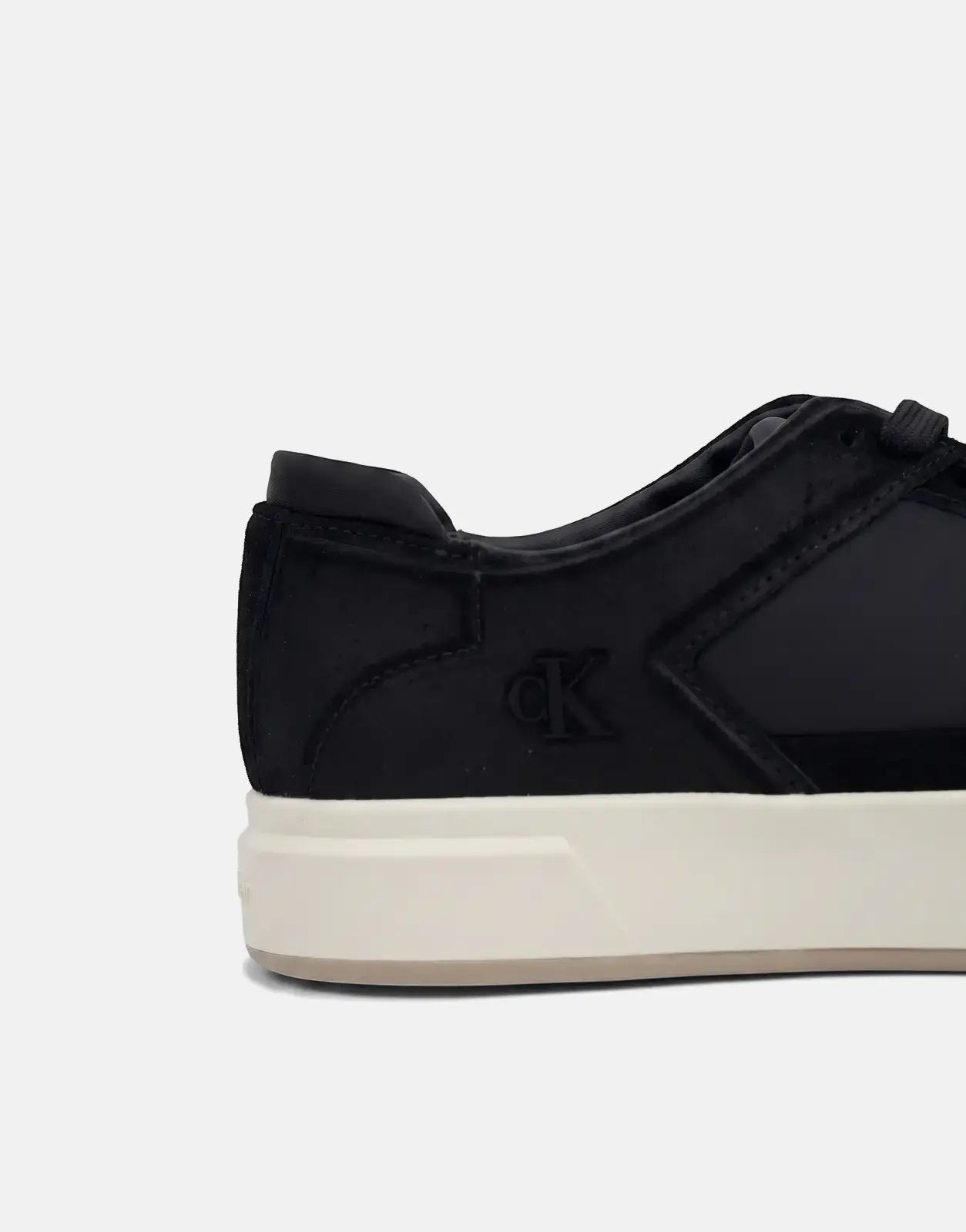 Close-up profile of a black Calvin Klein Basket Cupsole sneaker featuring suede and synthetic panels with a cream sole,