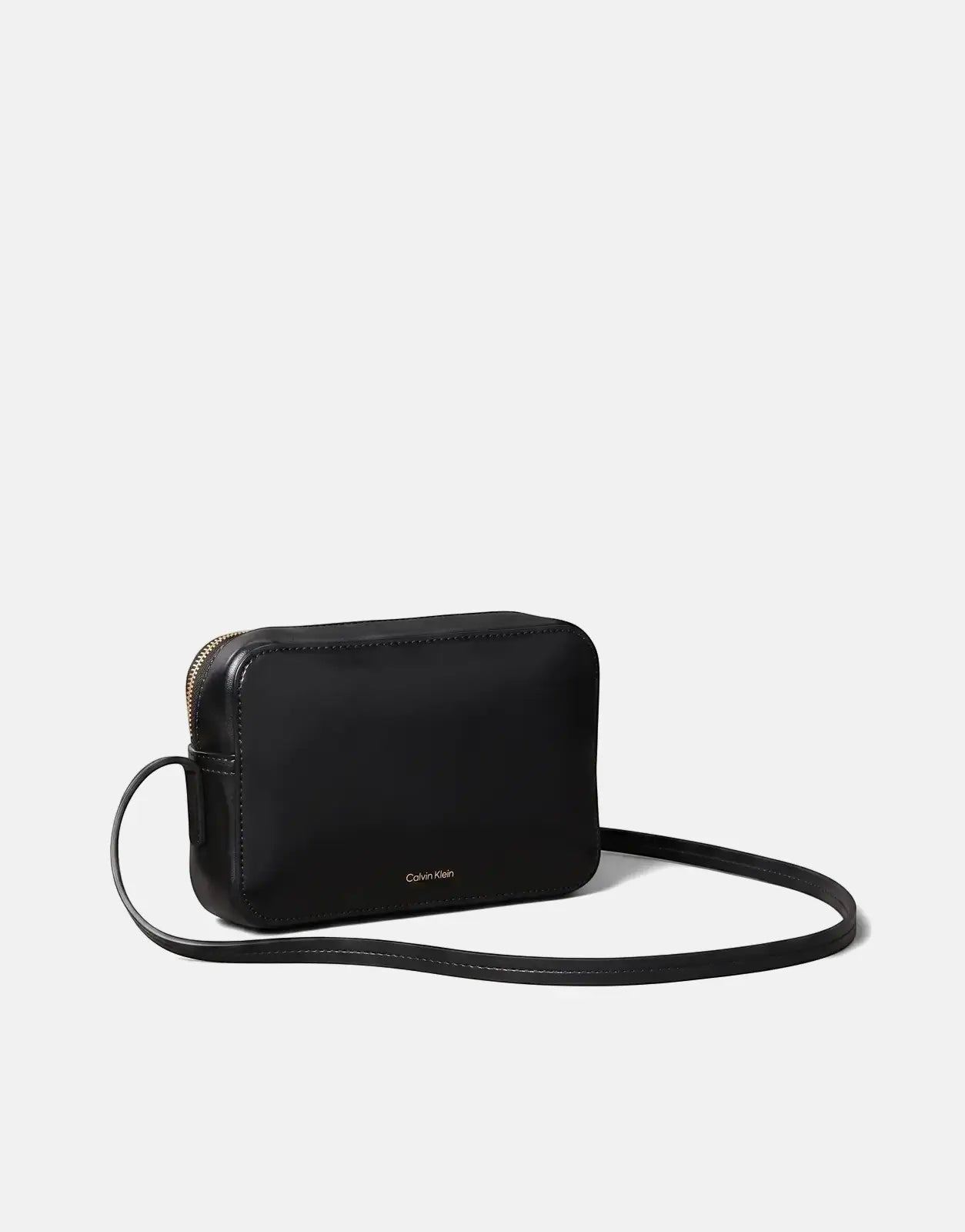 Black Calvin Klein camera bag with a rectangular shape, featuring a gold-tone zipper and an adjustable shoulder strap.