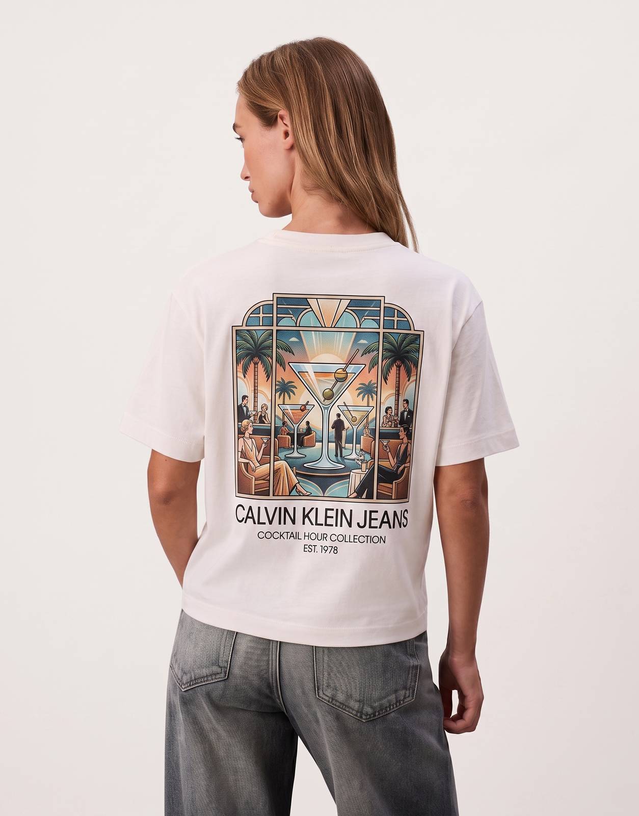 Calvin Klein Boxy Cocktail Logo White T-Shirt on a female model, shown from the back, highlighting the relaxed fit and