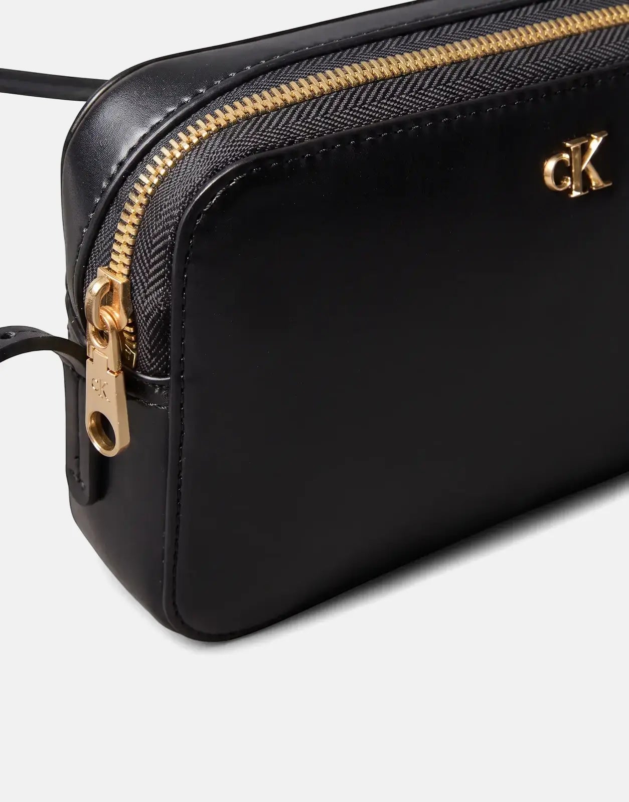 Close-up of a black Calvin Klein camera bag featuring a golden zipper and a prominent golden CK logo on the front.