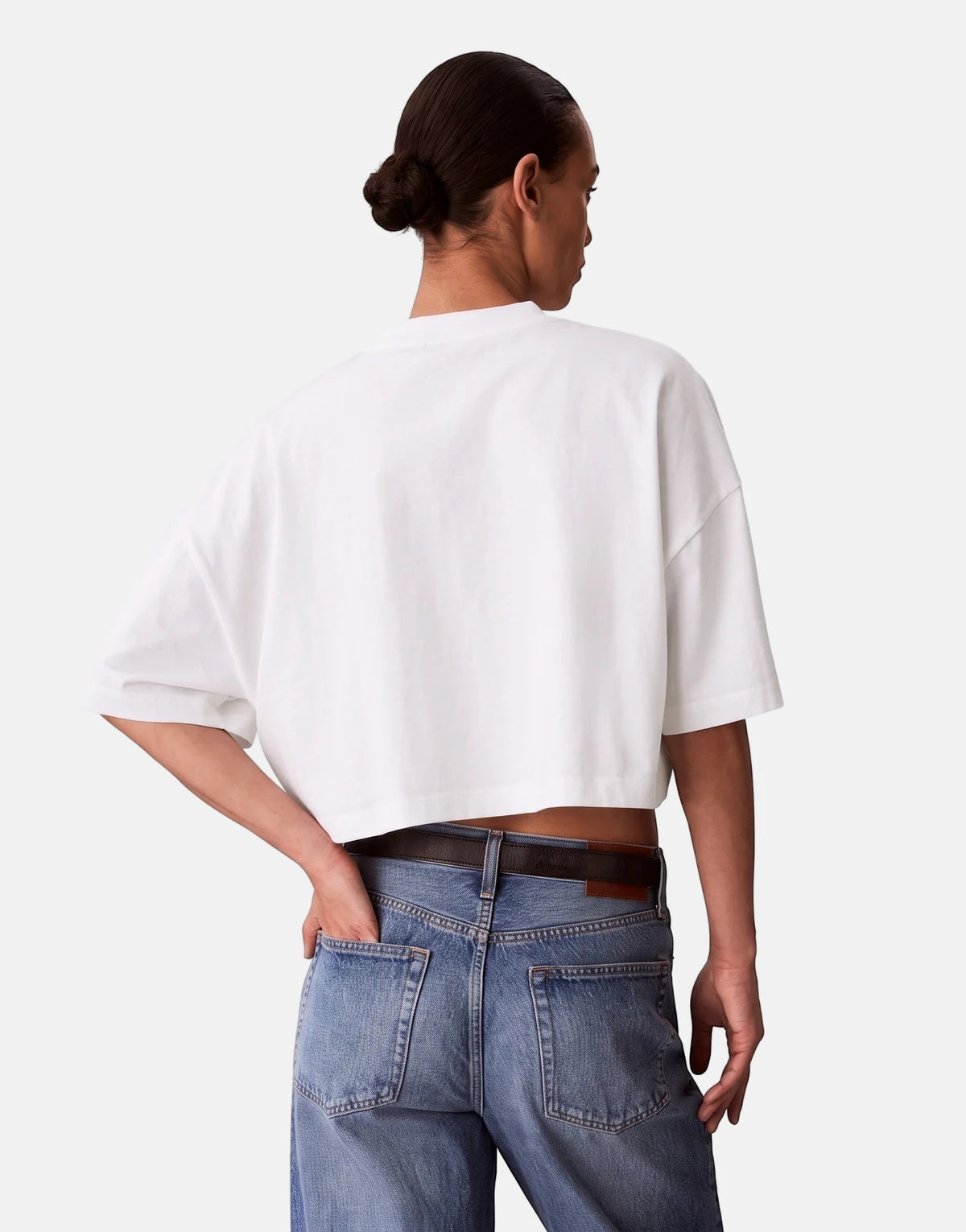 Women's Calvin Klein Cropped Boxy Heritage Crest Logo White T-Shirt, worn with blue jeans, viewed from the back.