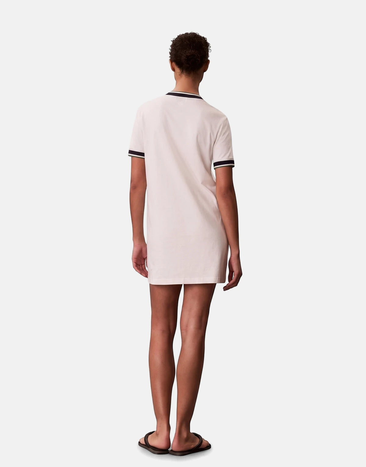 Off-white Calvin Klein CTN Monogram Stripe Trim Mini Dress on a model, seen from the back. Features short sleeves and ribbed