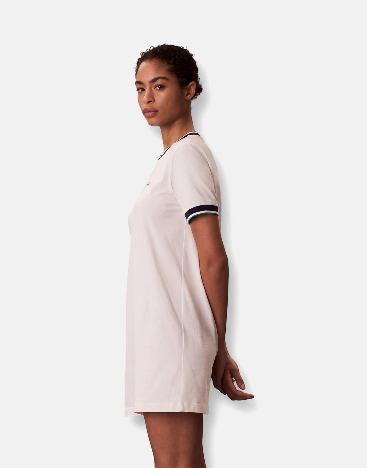 Woman wearing an off-white Calvin Klein CTN Monogram Stripe Trim Mini Dress made of cotton, shown in a side profile.