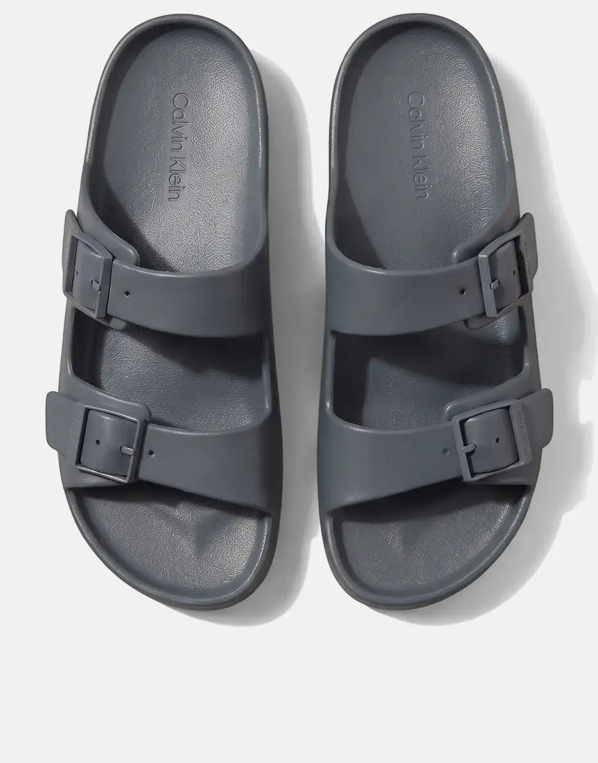 A pair of Calvin Klein Ergon Eva Double Bar sandals in blue-grey, shown from a top-down view.