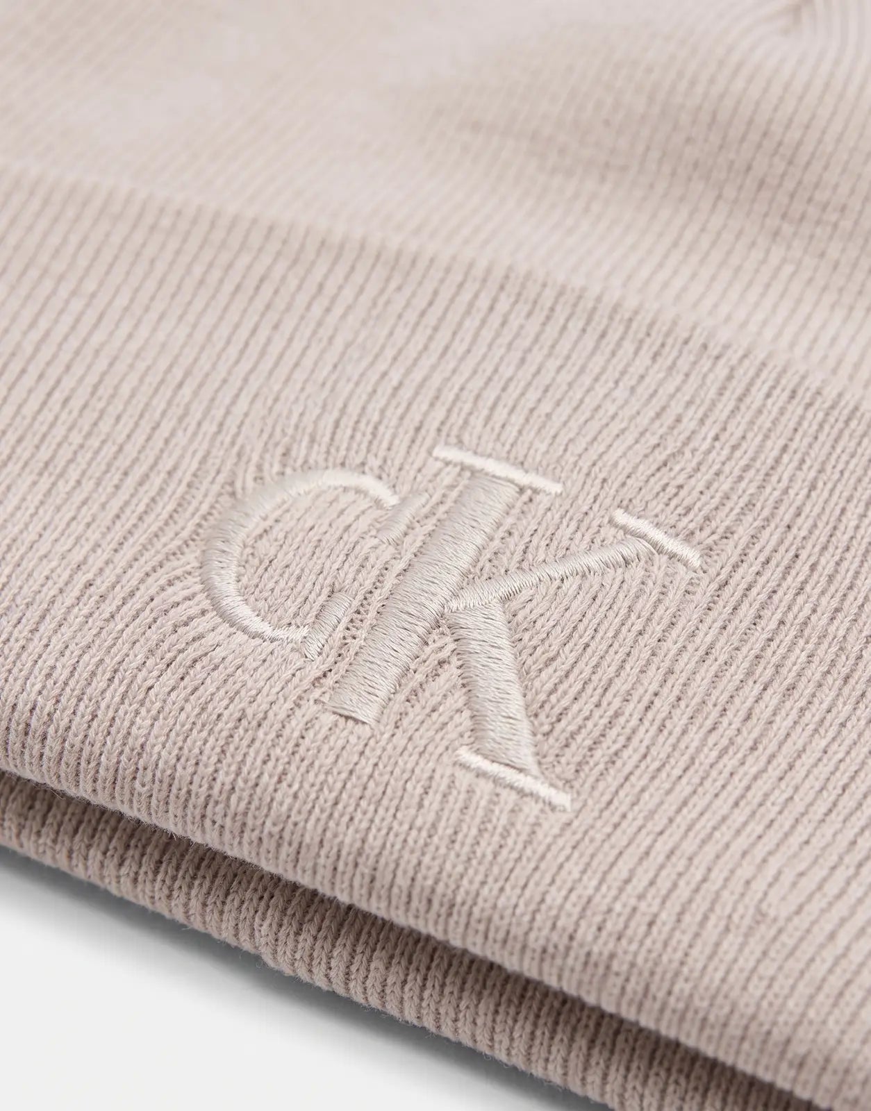 Calvin Klein Fine Rib Beige Beanie in ribbed knit fabric with tonal CK logo embroidery, close-up view.