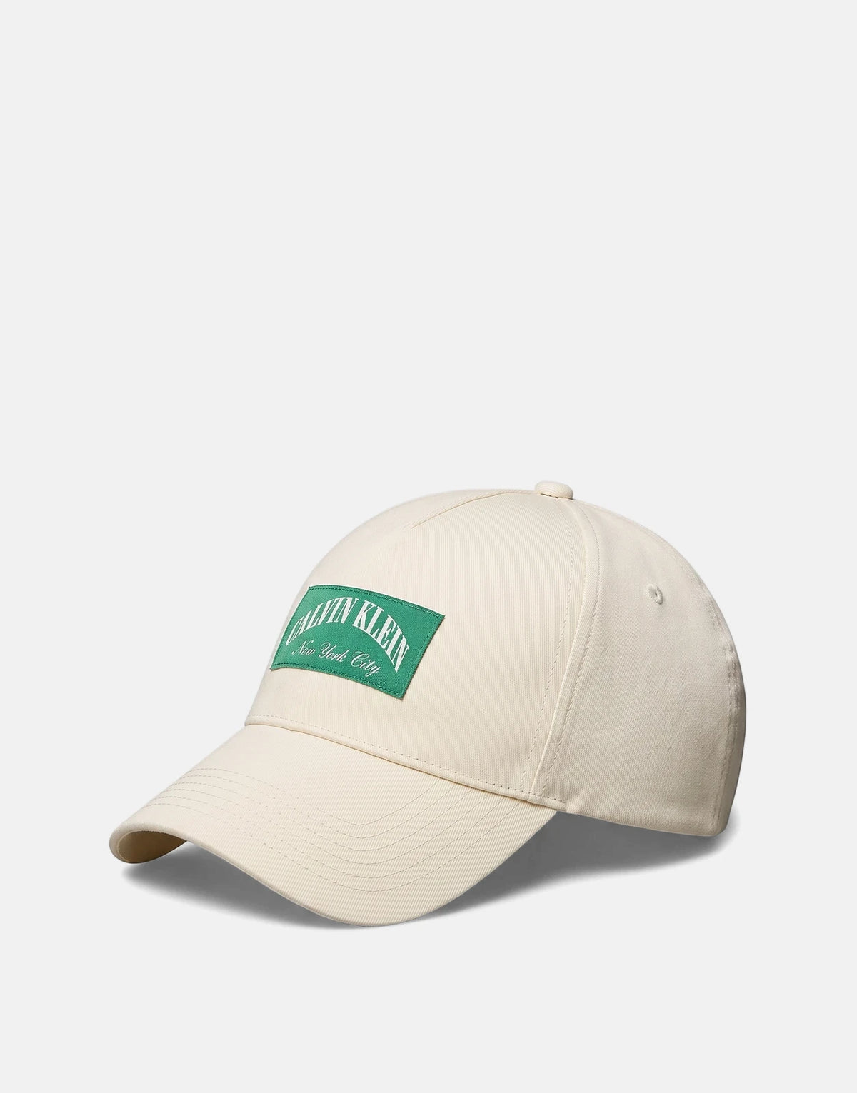 Calvin Klein Heritage Crest Off White Pitch Cap with a green logo patch, captured from an elevated perspective.