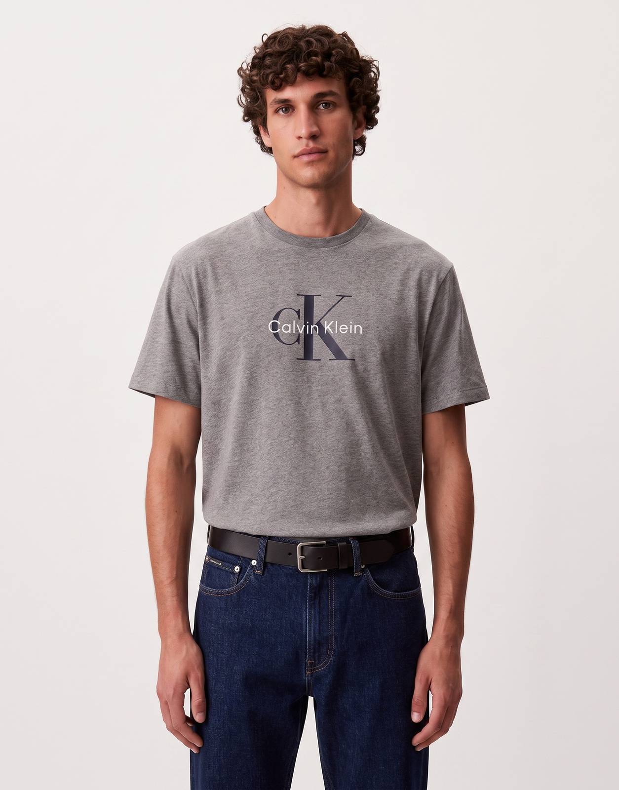 A male model wearing a grey Calvin Klein Hero Monologo t-shirt, featuring short sleeves and a crew neck, displayed front-on.