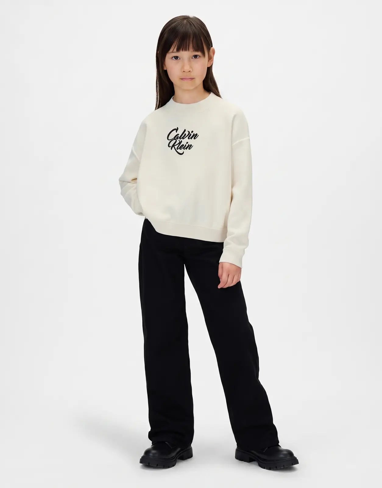 Calvin Klein Kids Script Logo Sweatshirt in cream, front view. A child models the long-sleeved crew neck top.
