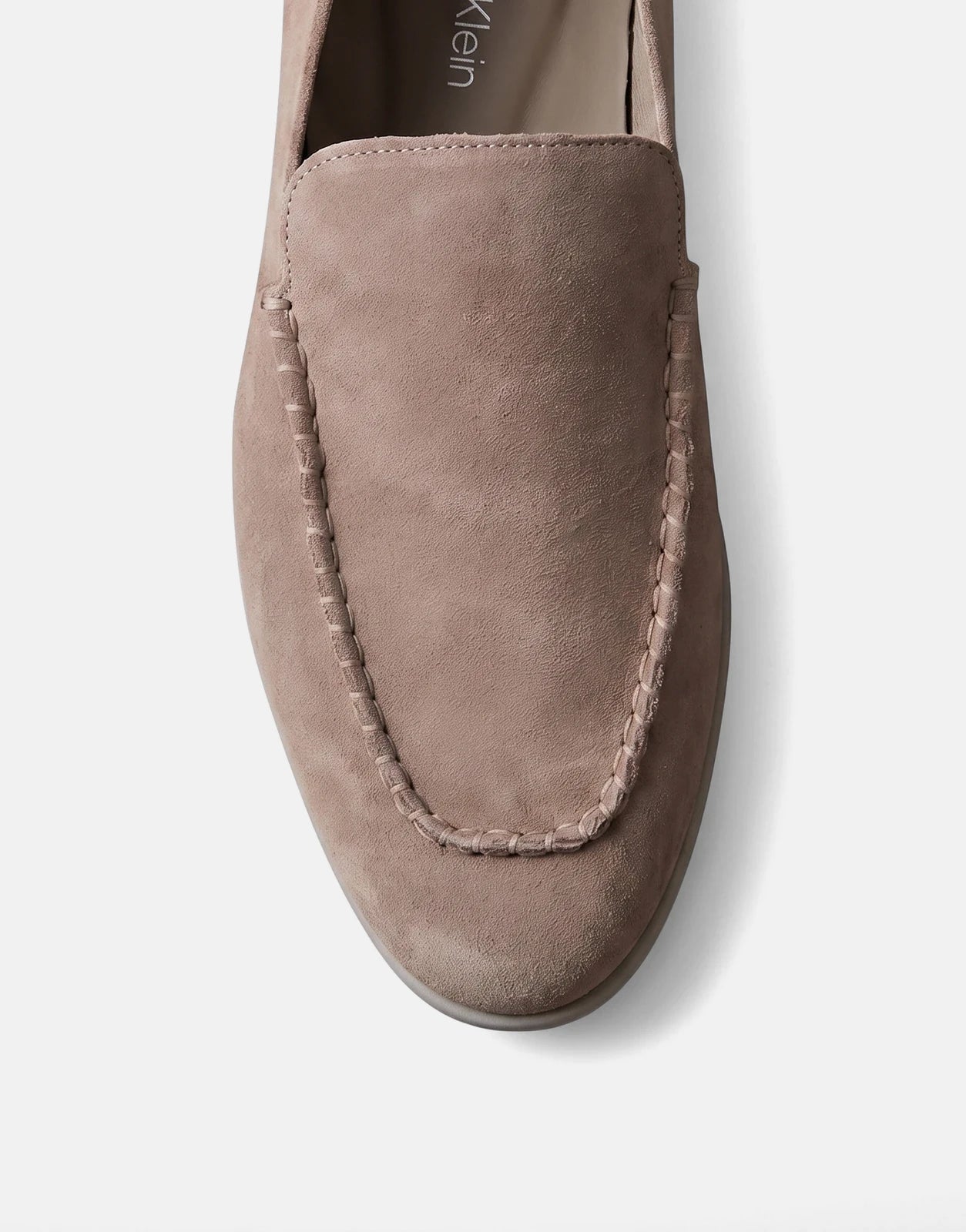 Front view of a Calvin Klein Low Prof taupe suede loafer, showcasing its intricate stitching and comfortable design.