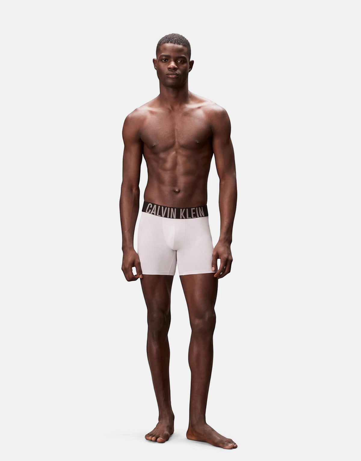 A male model wearing white Calvin Klein boxer briefs, showcasing the comfortable fit and branded waistband.