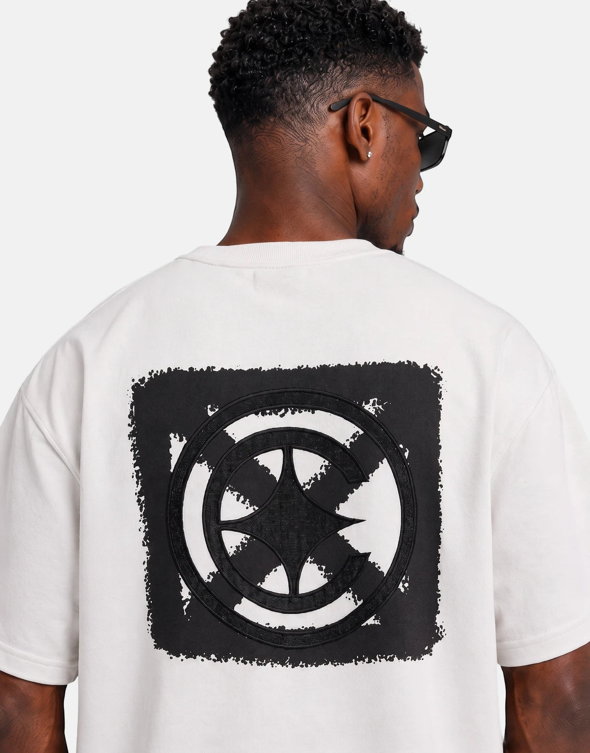 Covali Denimo White T-Shirt worn by a model from the back, showcasing a black textured graphic print on the reverse.