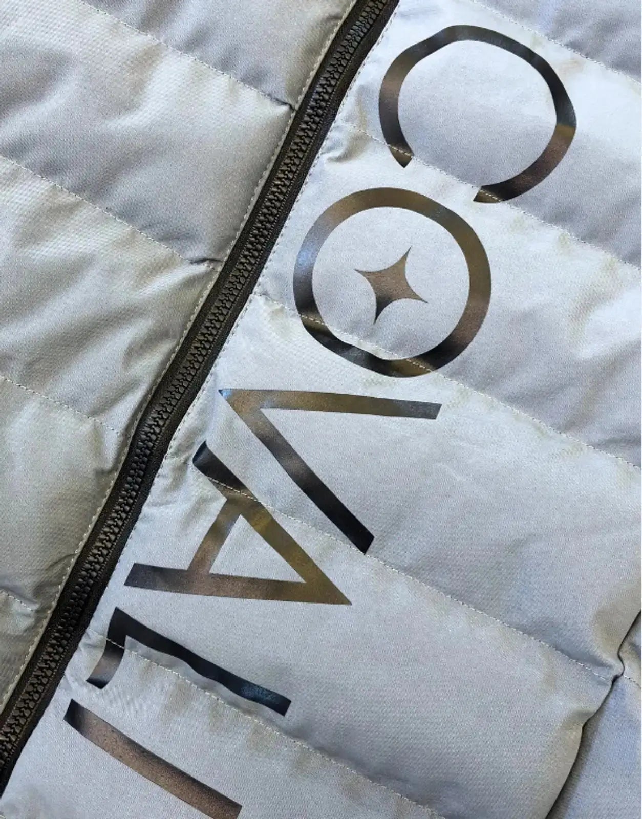 Close-up of a light grey Covali Inverno puffer jacket featuring visible quilting, a black zipper, and the Covali brand logo.