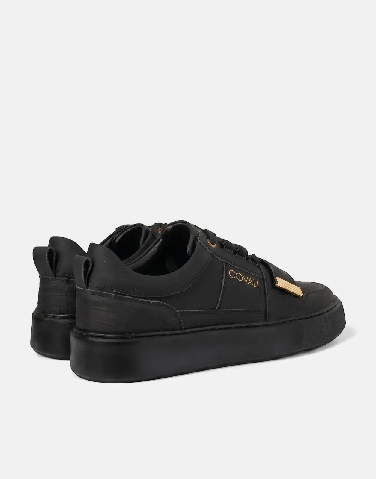 Covali Moda black leather low-top sneakers with gold logo and accents, viewed from the side with a slight angle.