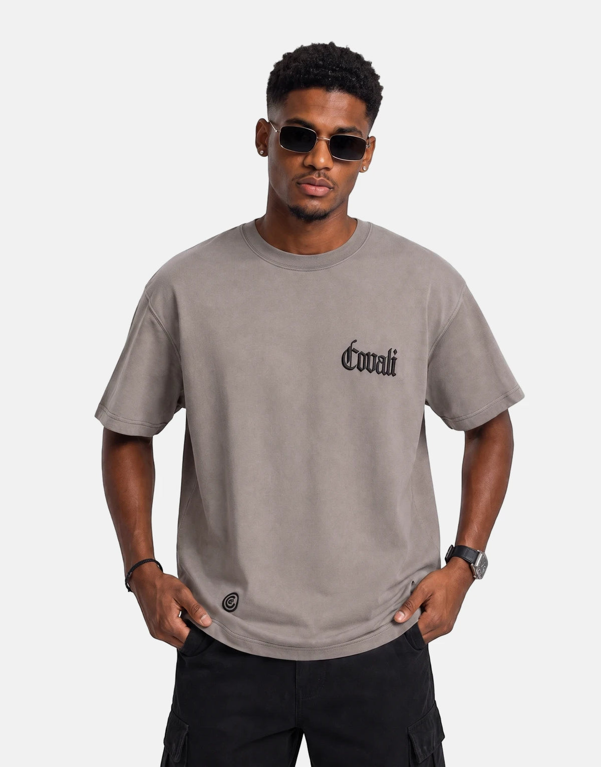 Male model wearing a Covali Punto Grey T-Shirt with black sunglasses and cargo pants, hands in pockets.
