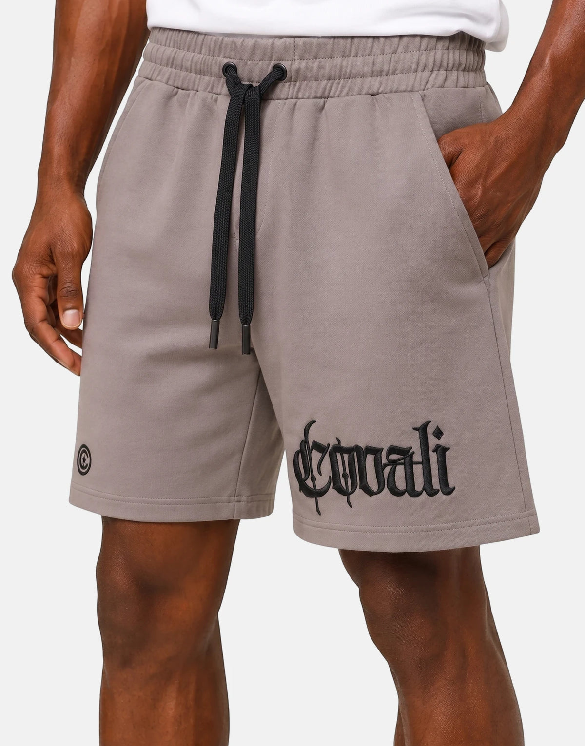 Men's Covali Punto Sand Shorts in taupe fleece material, featuring a black drawstring, side pockets, and gothic script logo.