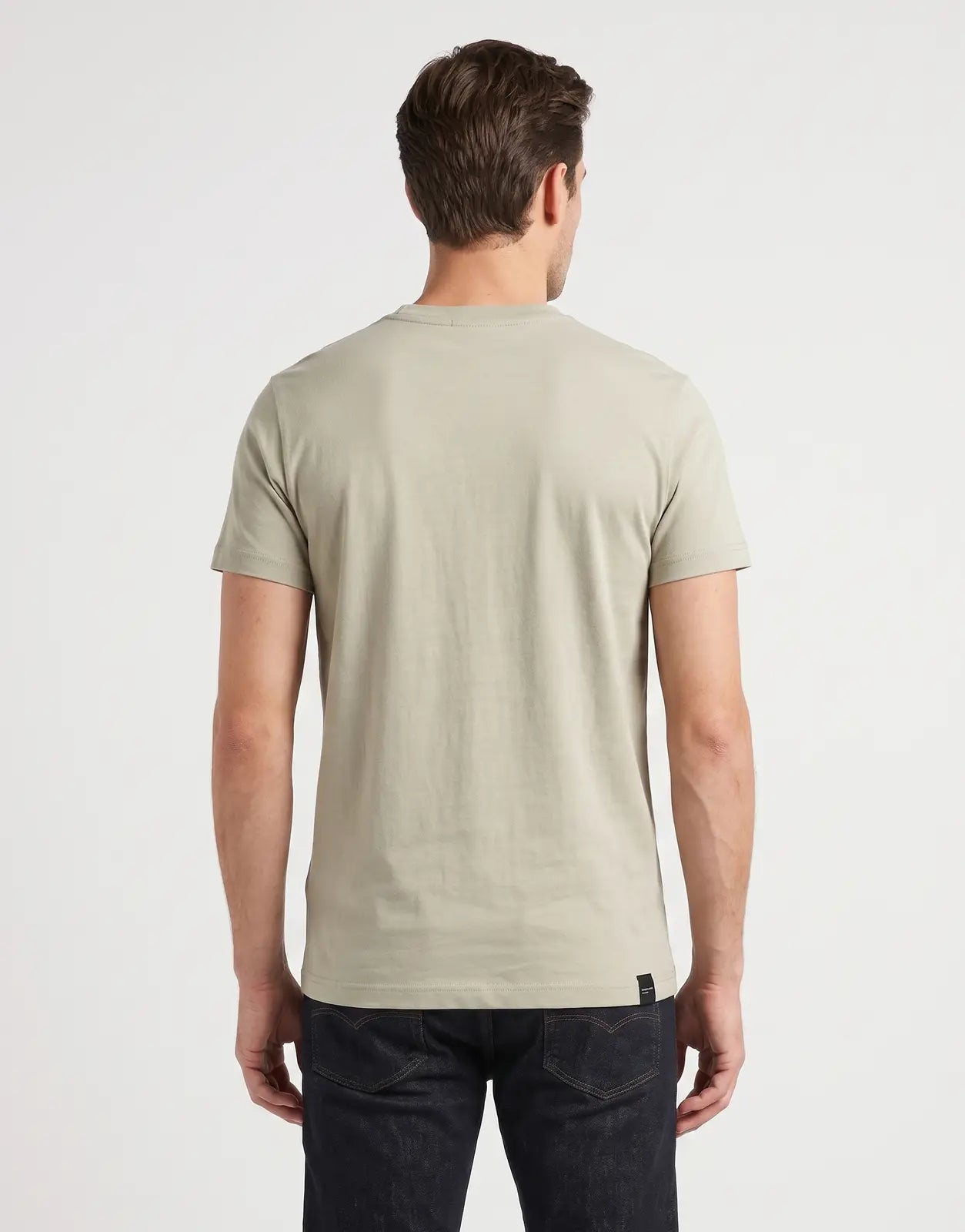 Rear view of a male model wearing a Covali Tipo A Moss T-shirt, made from soft cotton, paired with dark jeans.