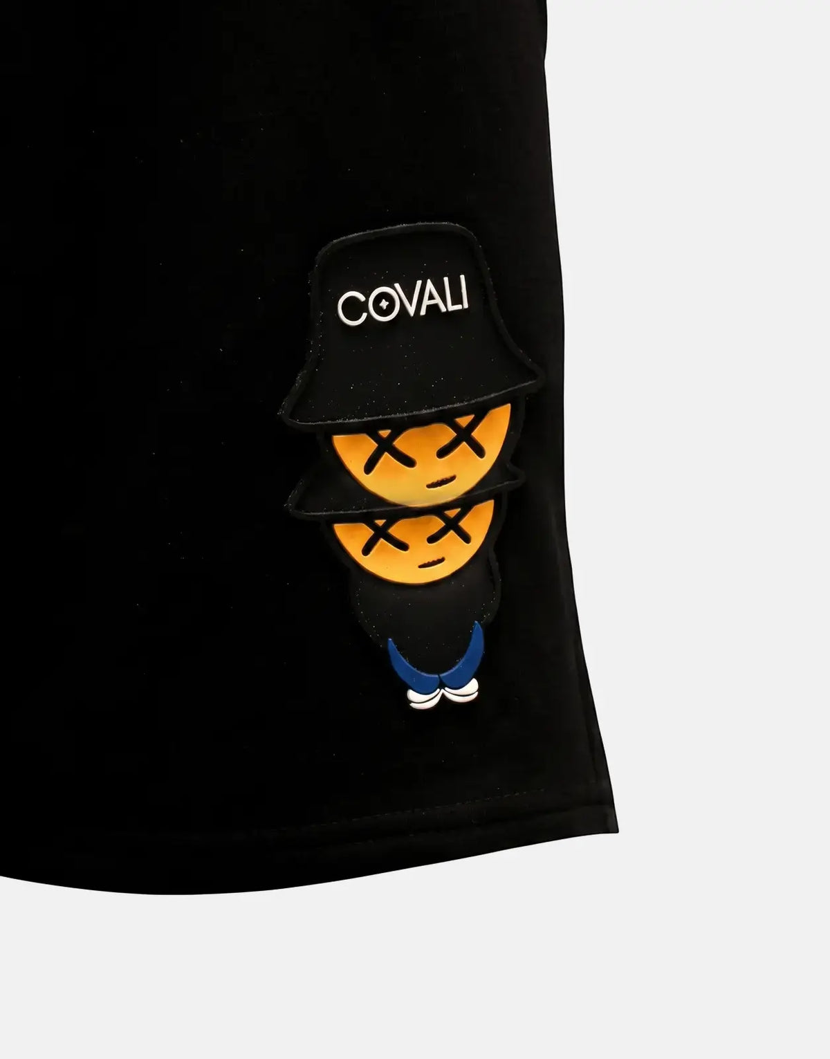 Covali Tipo V black short featuring a unique 'COVALI' hat logo and two orange 'X' eye smiley patches, close-up view.