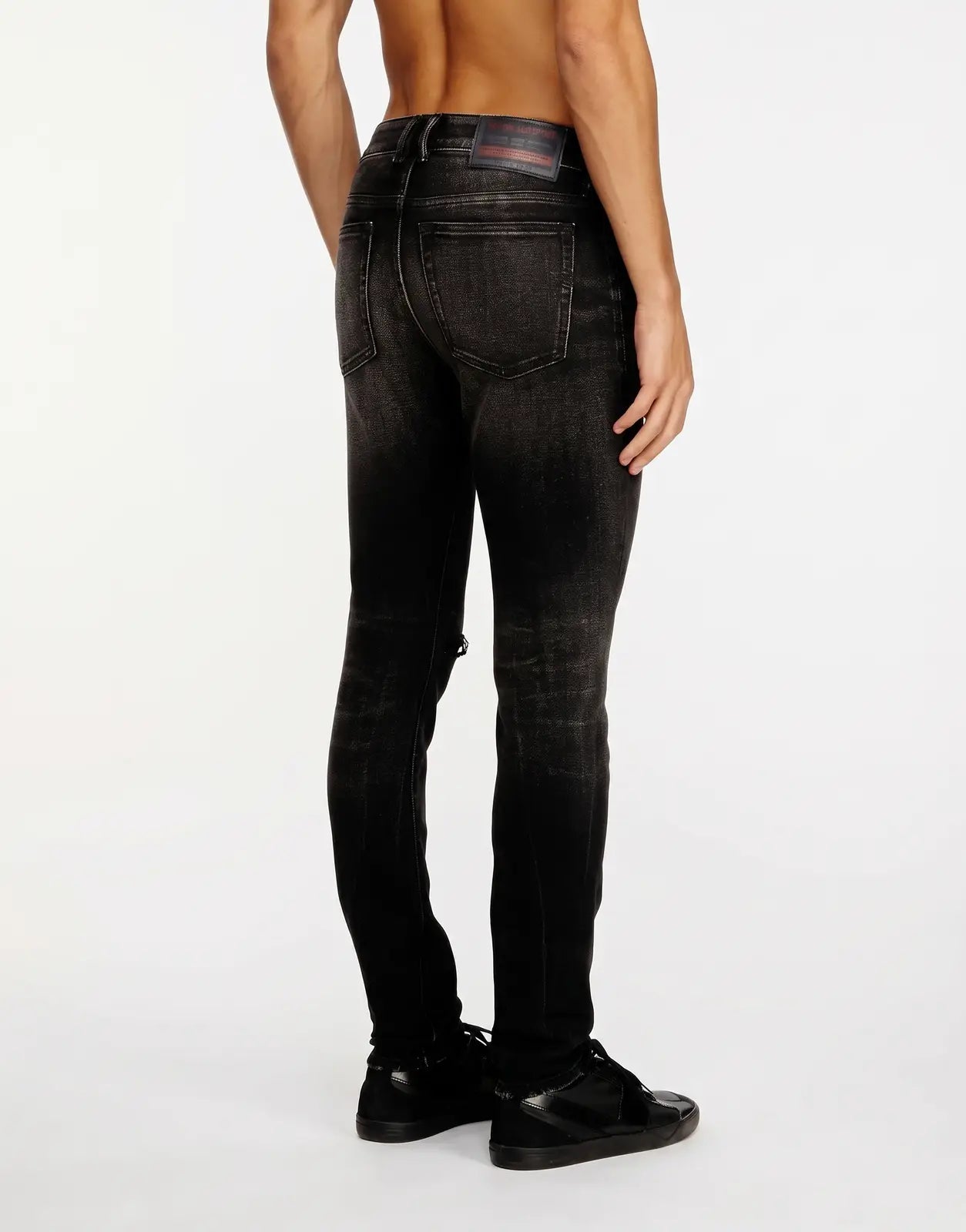 Diesel 1979 Sleenker black distressed skinny denim jeans for men, back/side view on model, with ripped knee and rear