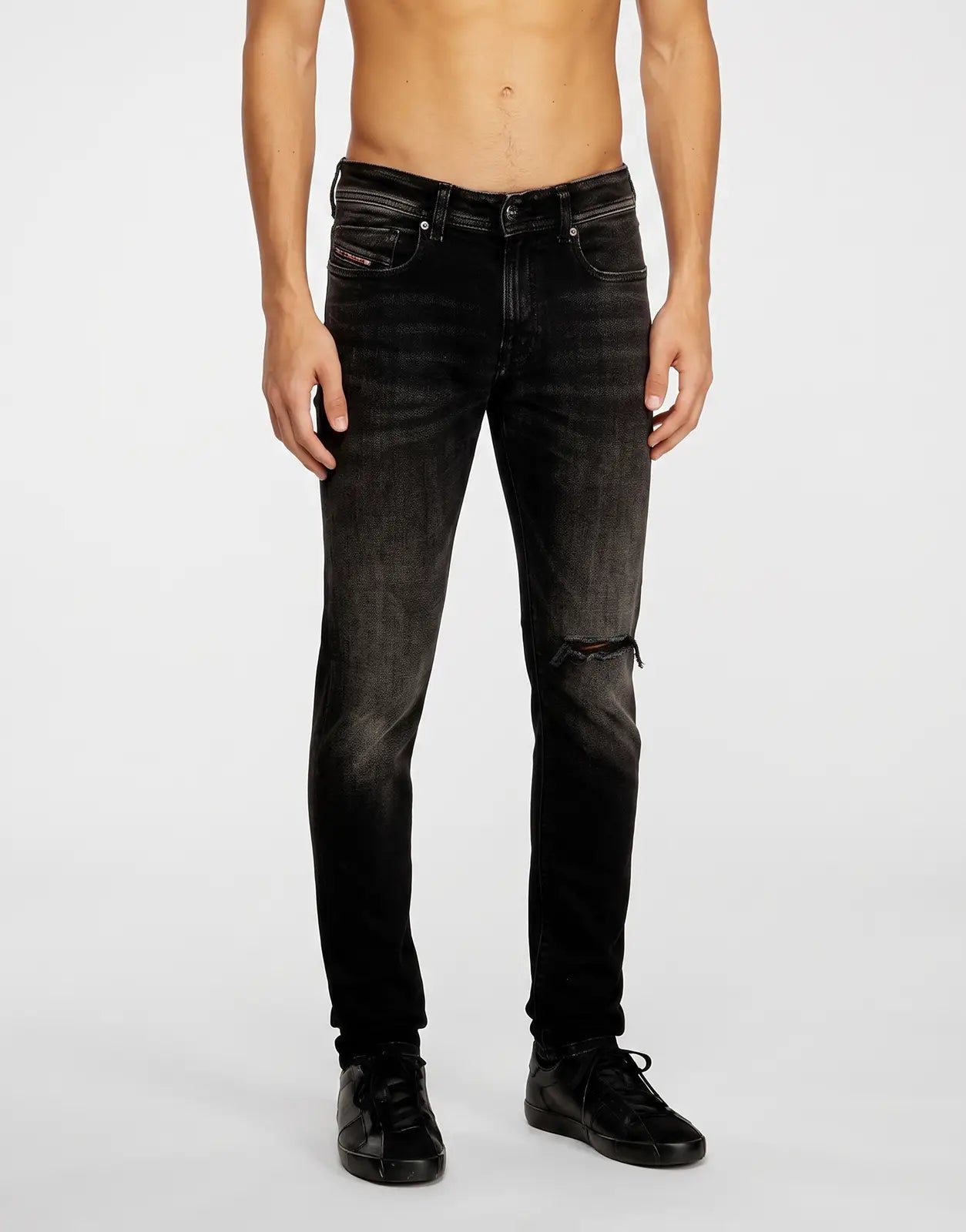 Men's Diesel 1979 Sleenker skinny denim jeans in black, featuring a distressed finish and a torn knee detail, front view.