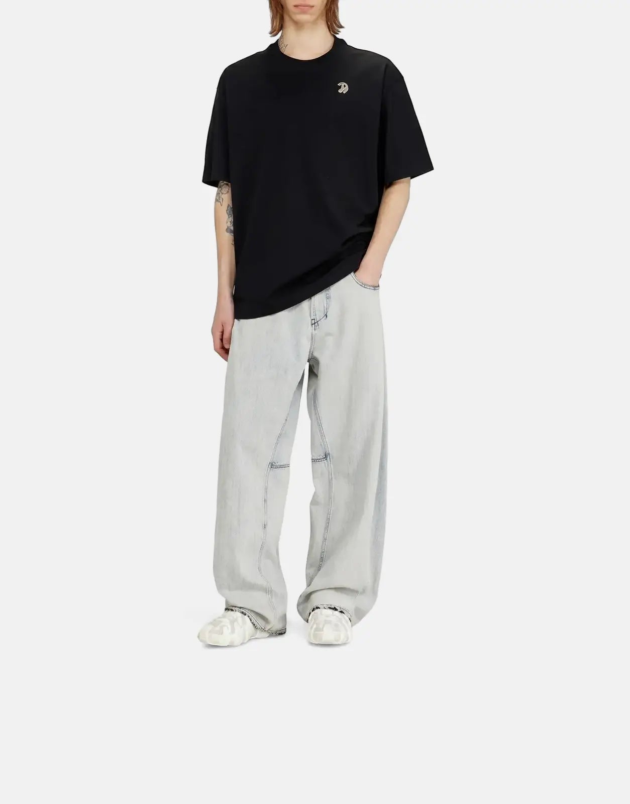 Male model wearing a black Diesel T-Boggy V2 short-sleeve t-shirt with a metallic logo, paired with light wash baggy jeans.