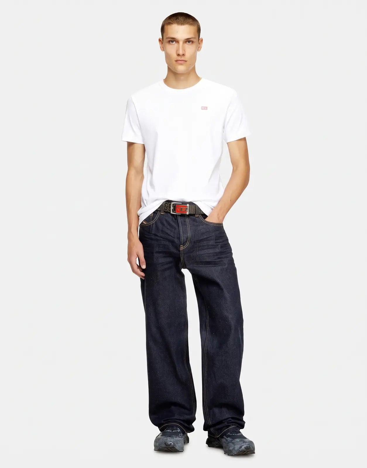 Men's white Diesel T-Miegor K77 t-shirt with a small red logo, paired with dark wash loose-fit jeans and a Diesel belt,