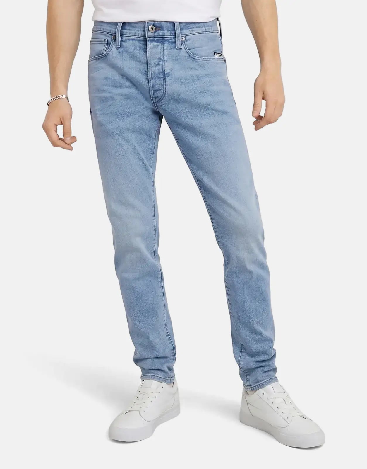 Person wearing G-Star RAW 3301 Slim Lt Aged Jeans, a light blue, slim-fit denim pant, paired with white sneakers.