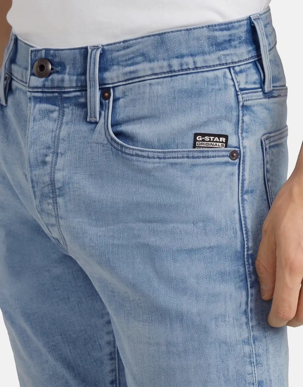 Close-up of a person wearing G-Star RAW 3301 Slim Lt Aged Jeans in a light blue wash, showcasing front details.