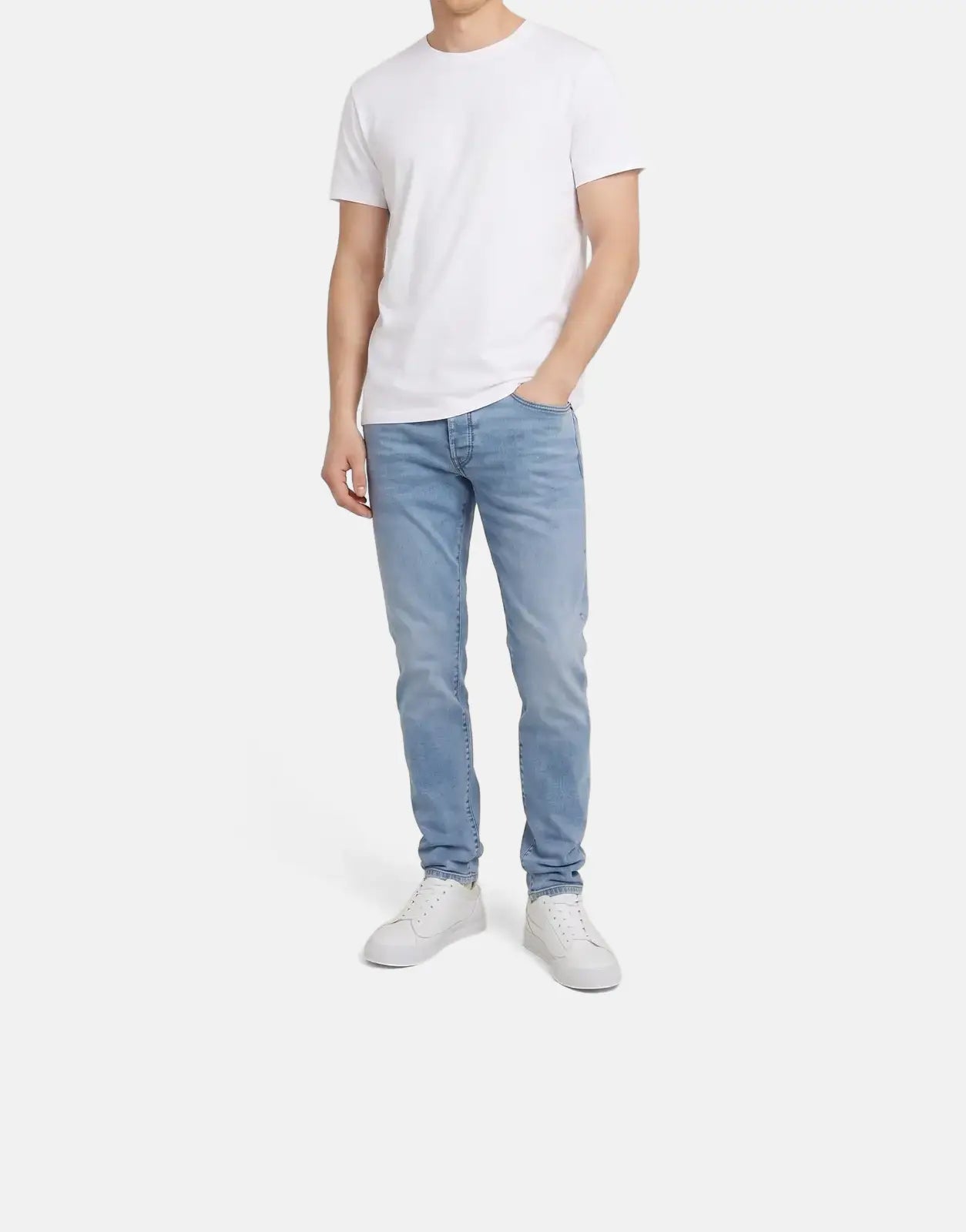 Full body shot of a man modeling G-Star RAW 3301 Slim Lt Aged Jeans paired with a crisp white t-shirt and white sneakers.