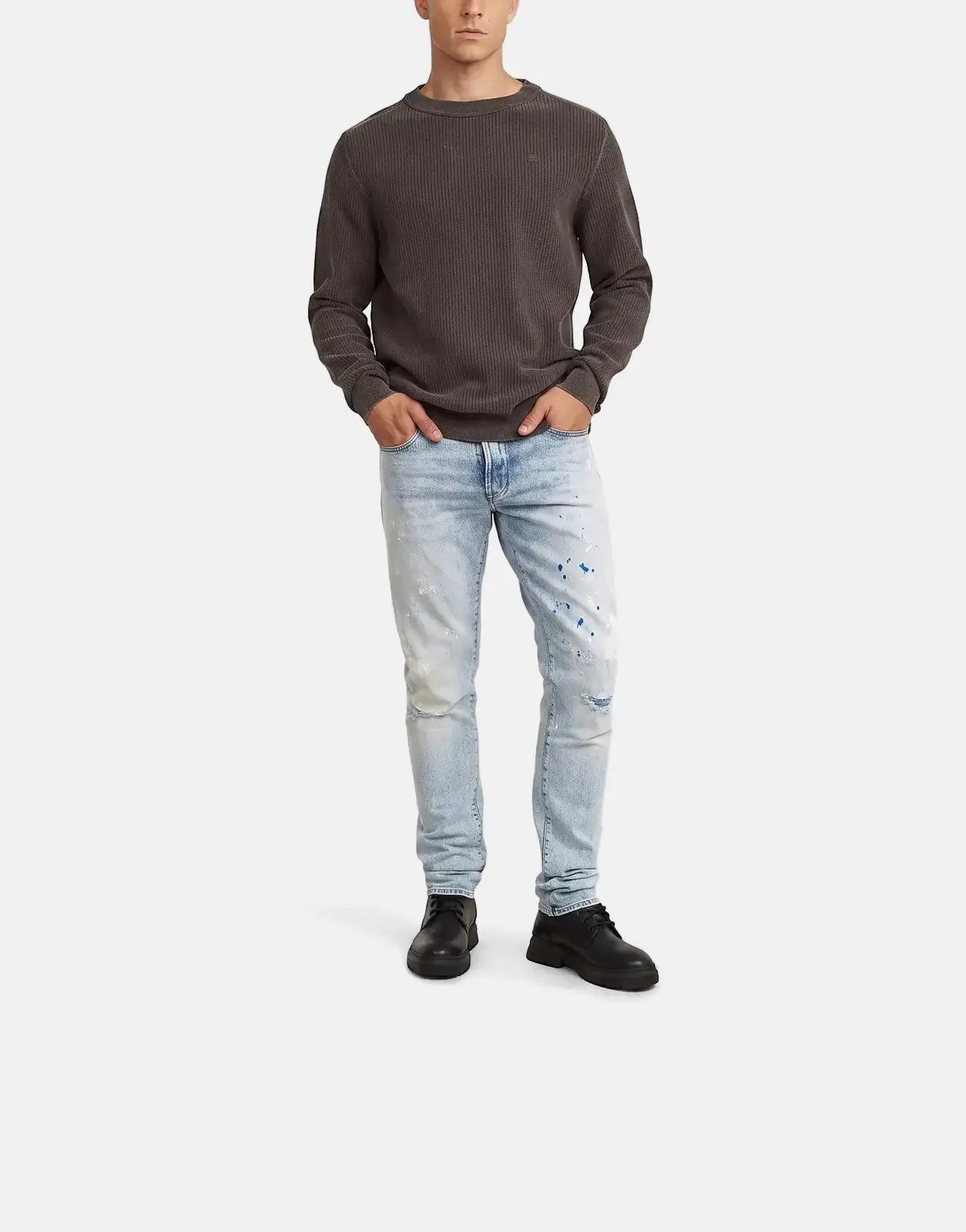 Front view of male model wearing G-Star RAW 3301 Slim Sun Faded Paint Blue jeans with a dark gray sweater.