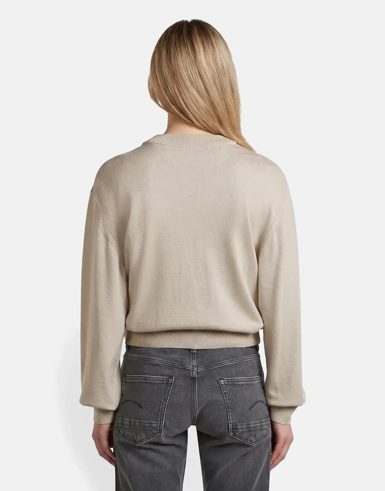 A woman from behind, wearing a beige G-Star RAW Boxy Knit Brick sweater with a ribbed crew neck and dark grey jeans.