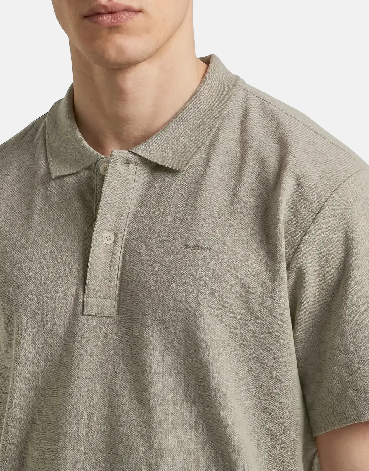 Close-up of a man wearing a G-Star RAW Core Regular Jacquard Polo Shirt in elephant skin color, featuring a short sleeve and