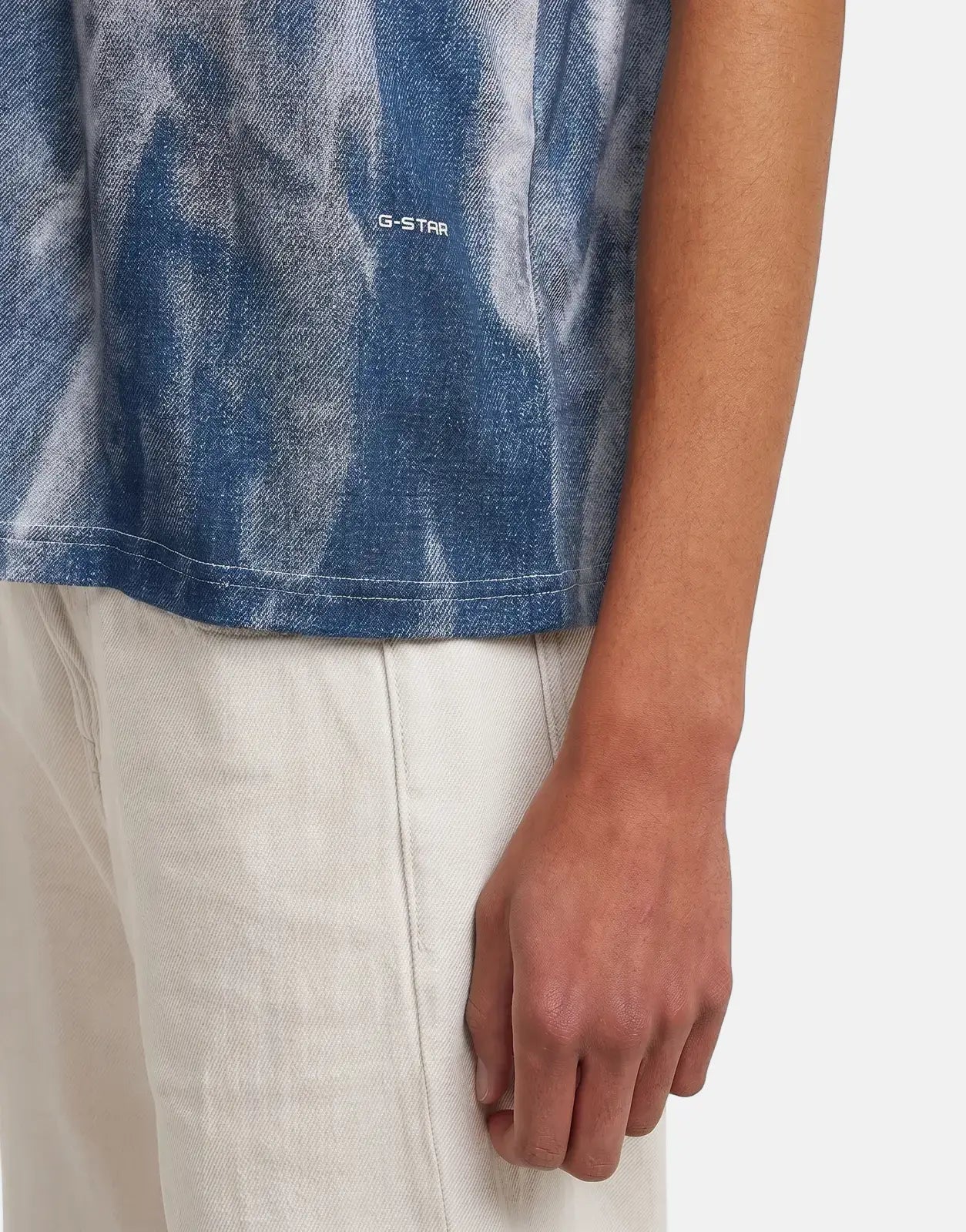 Close-up of a person wearing a G-Star RAW Denim Print Denim Flame T-Shirt in blue and white with the G-Star logo.