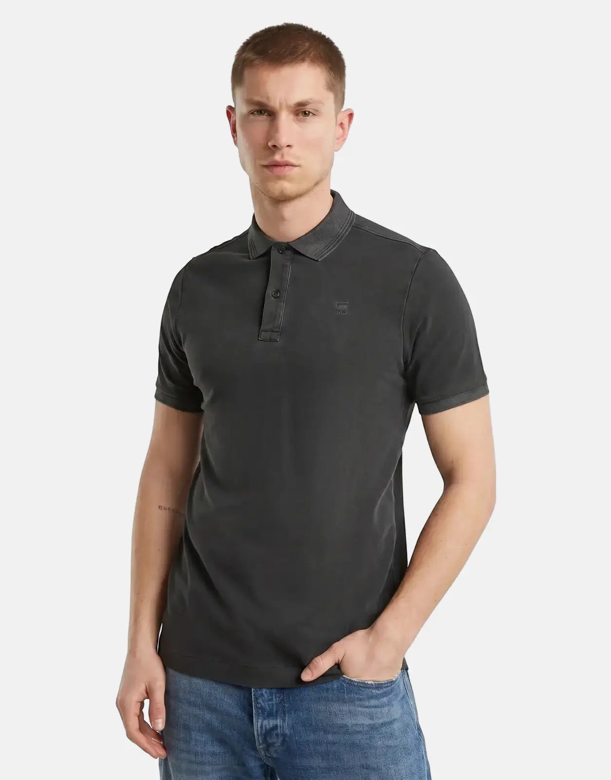 Male model wearing a G-Star RAW Dunda Overdyed Black Slim Polo Shirt, paired with blue jeans, photographed front view.