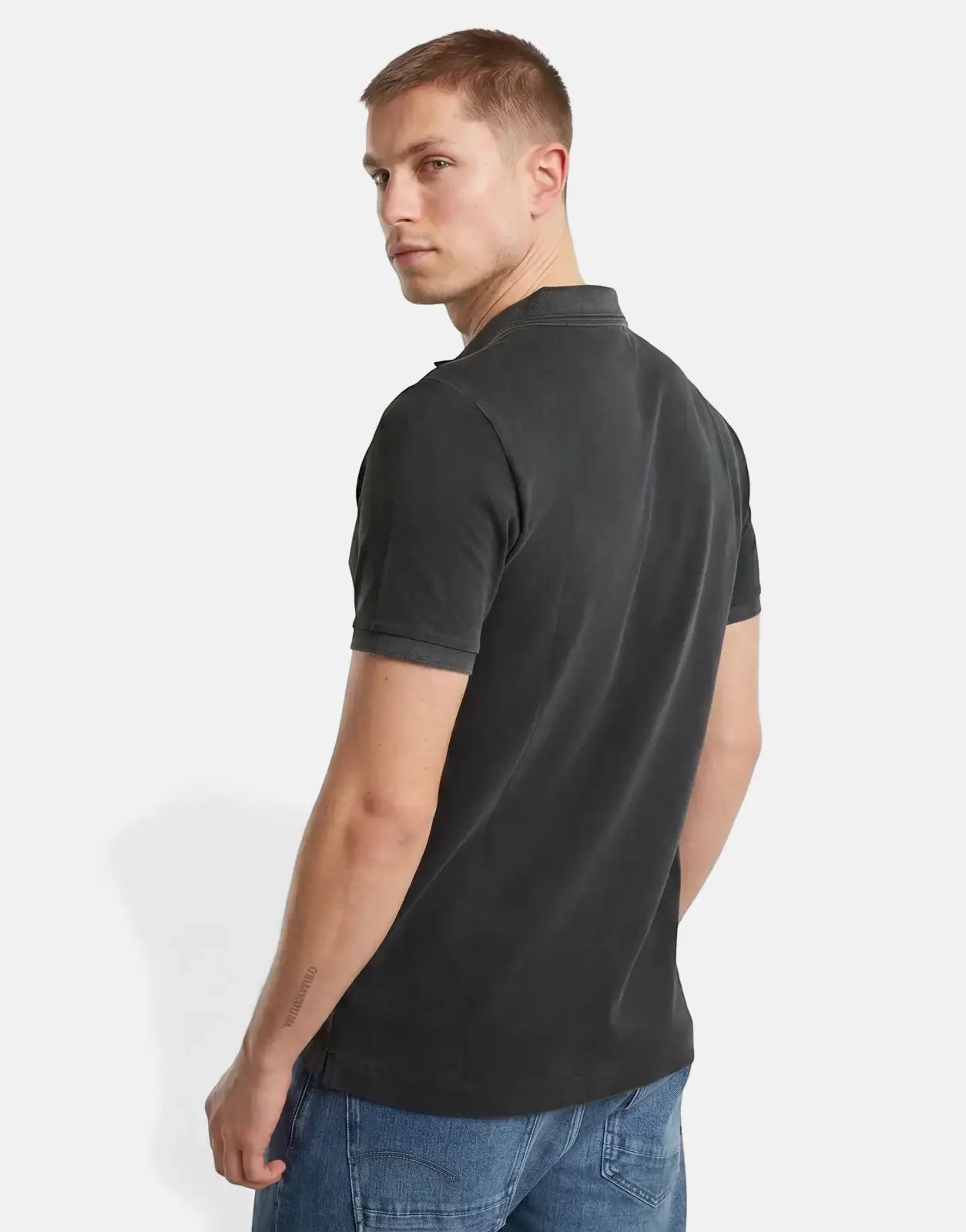 Male model wearing a G-Star RAW Dunda Overdyed Black Slim Polo Shirt, styled with blue jeans, viewed from the back.