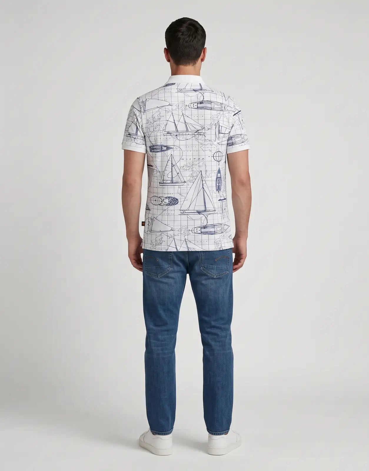 Back view of a G-Star RAW Dunda Slim AOP White Polo Shirt, featuring a detailed all-over print of blue maps and sailboats,