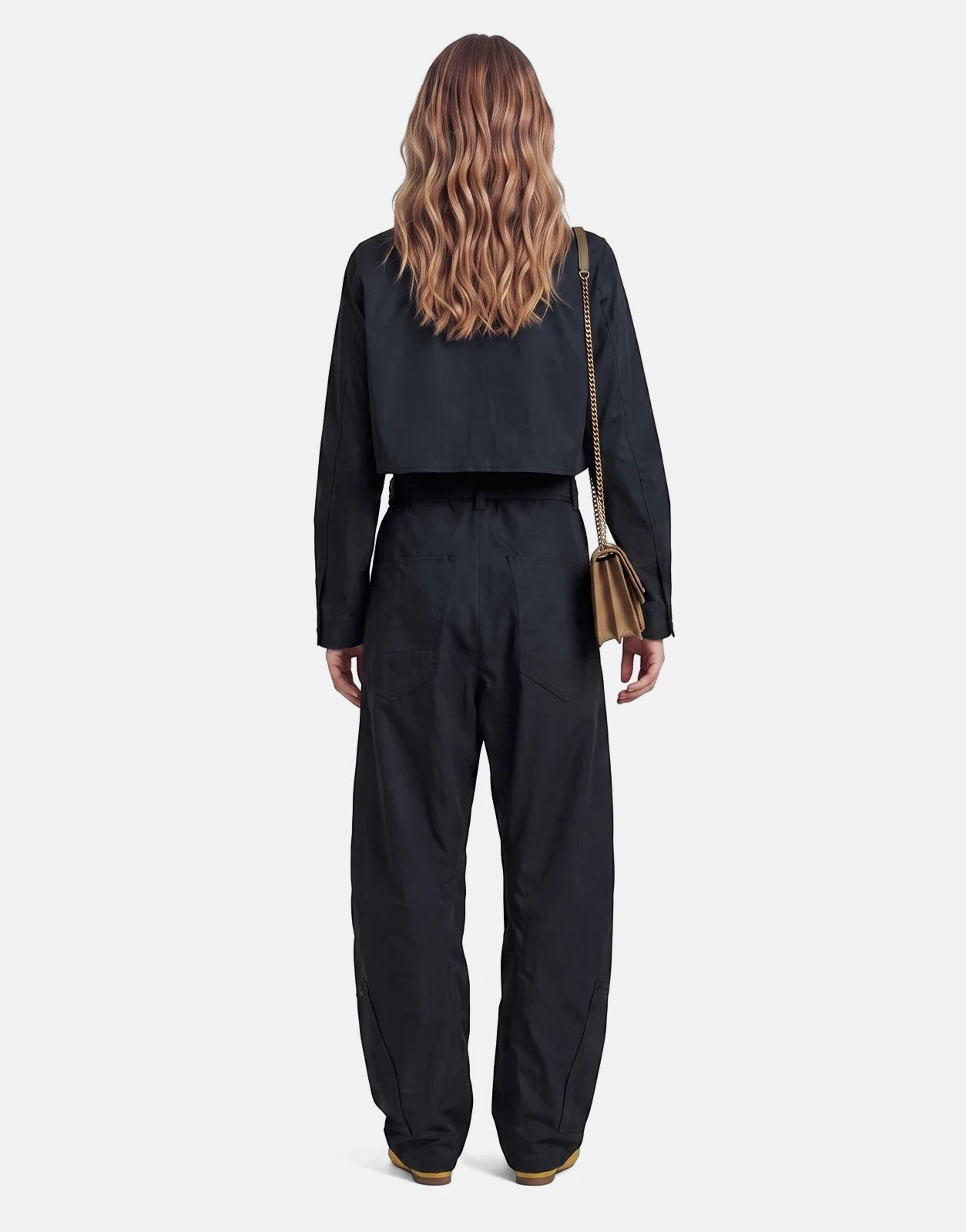 Rear view of a model wearing a black G-Star RAW Fightsuit Salute Jumpsuit, featuring a cropped jacket and wide-leg pants.