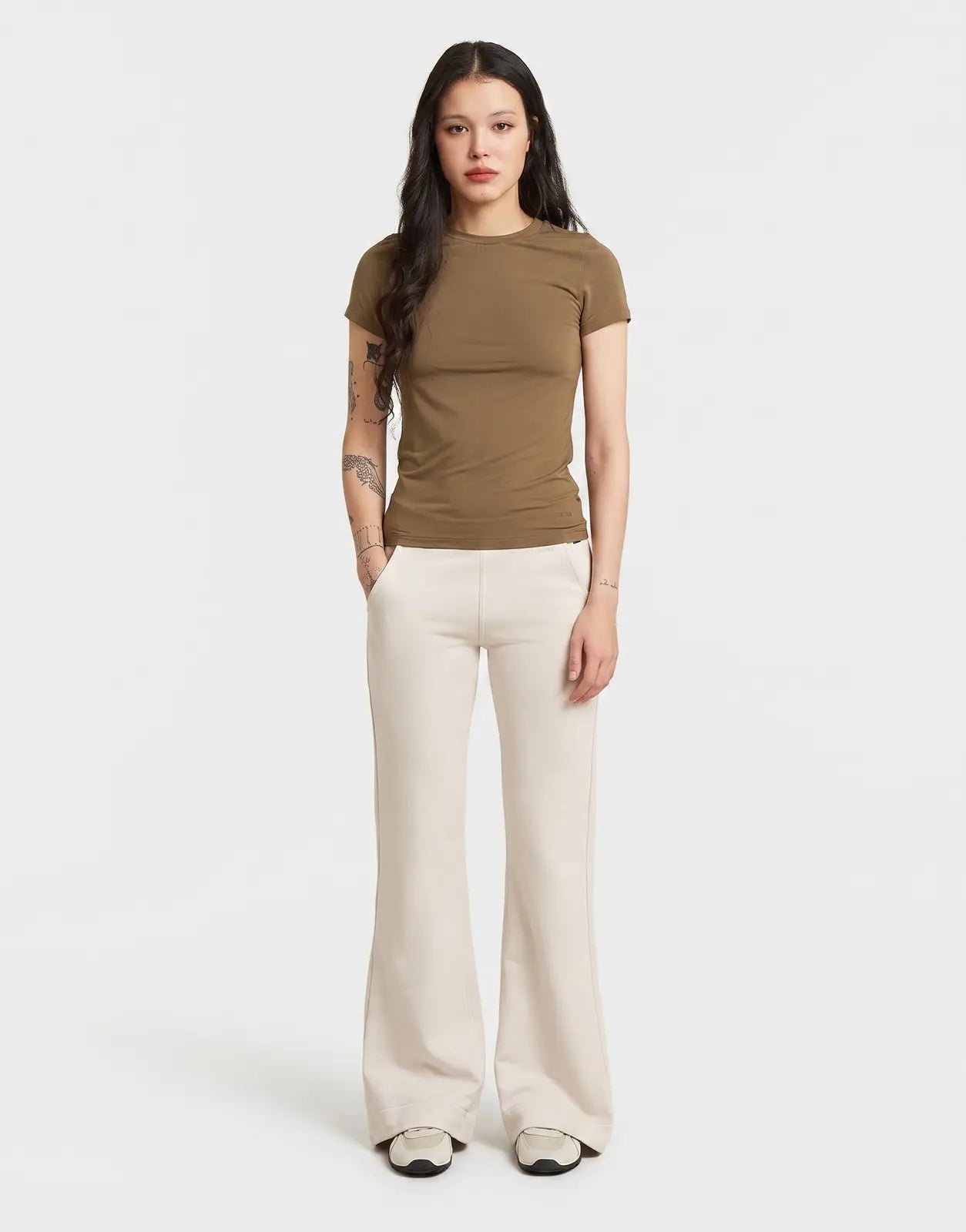 A woman wears G-Star RAW Flared Whitebait Sweatpants, a light off-white color, paired with a fitted brown t-shirt in a