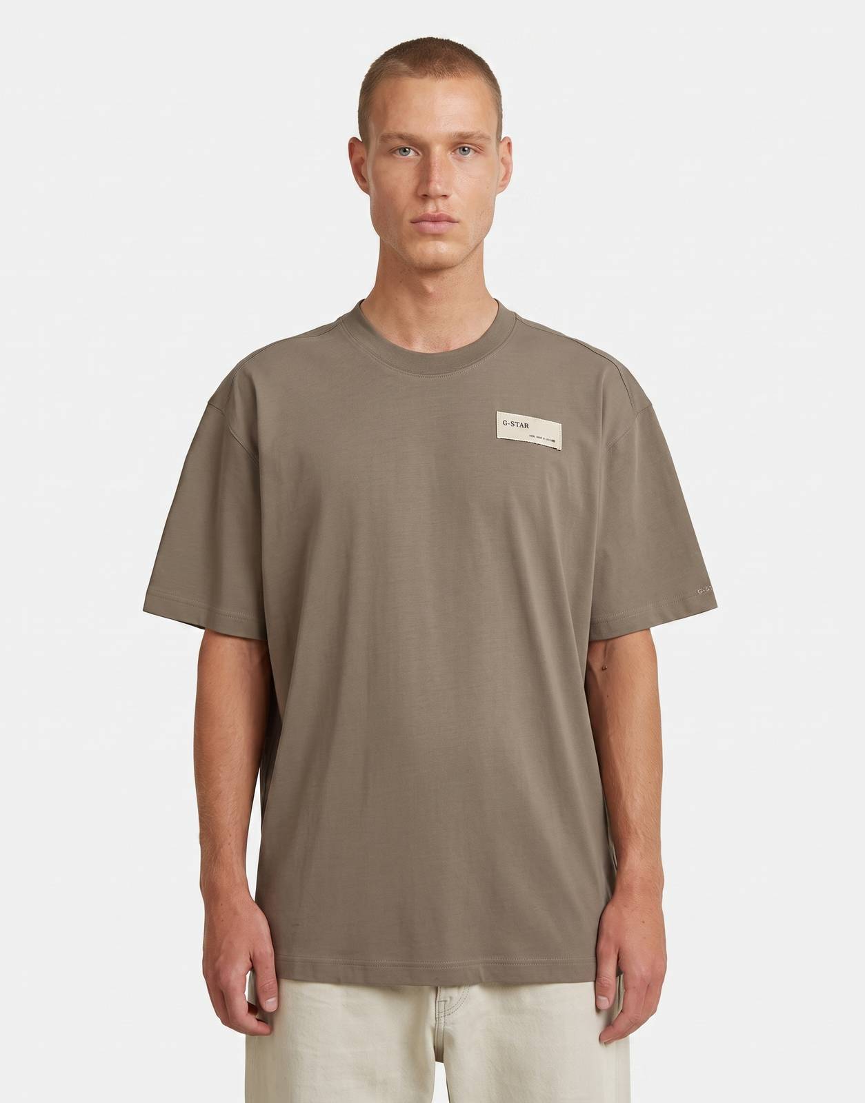 A male model wears a G-Star RAW HB Badge Relaxed Turf t-shirt in a brown/olive green color, front view.