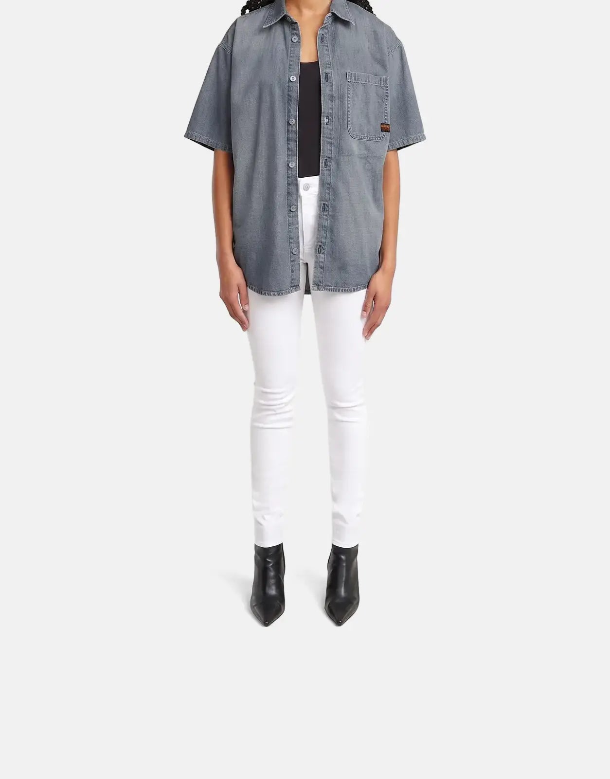 A female model wears G-Star RAW Lhana Skinny Paper White Jeans, paired with a blue-grey denim short-sleeve shirt and black