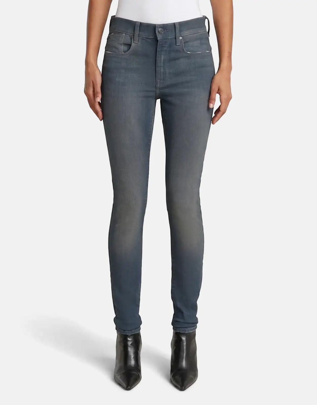 A person wears G-Star RAW Lhana skinny jeans in a worn smokey night blue. The jeans have a slim fit and visible stitching