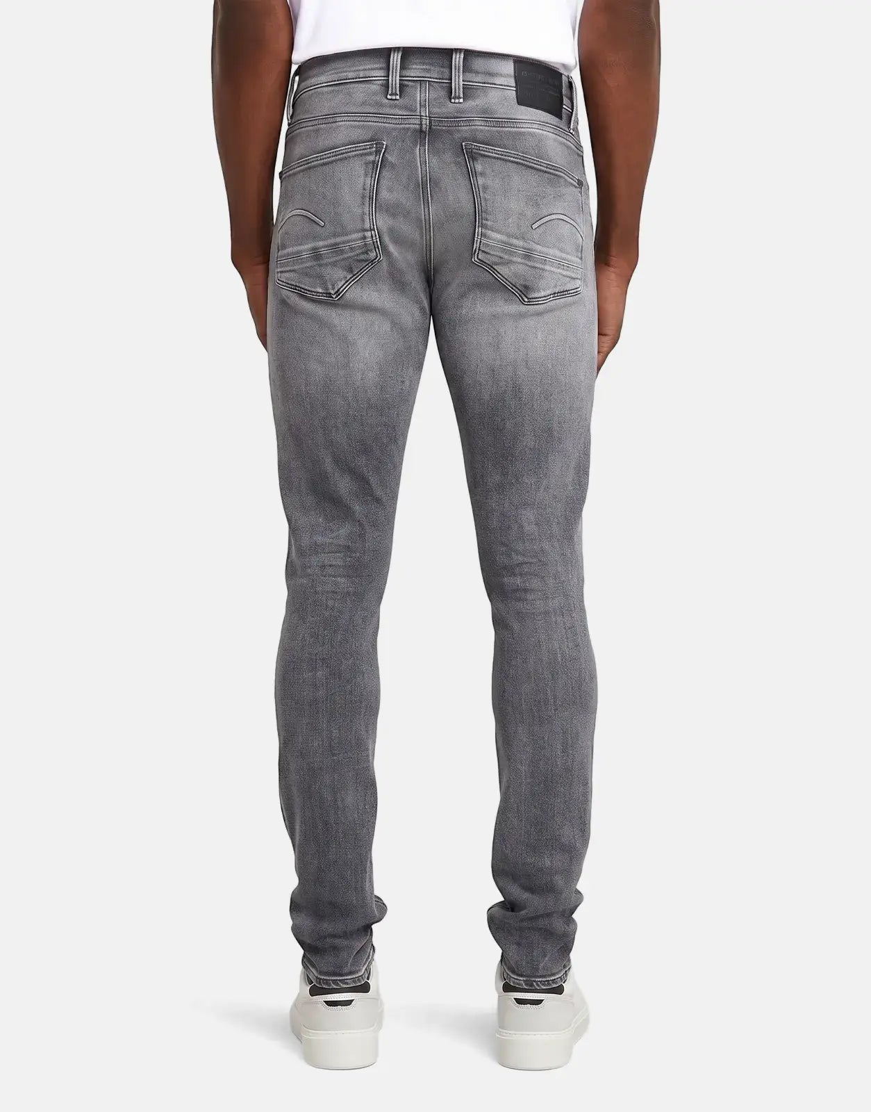 Men's G-Star RAW Revend FWD Skinny jeans in a faded shadow grey wash, shown from the back with white sneakers.