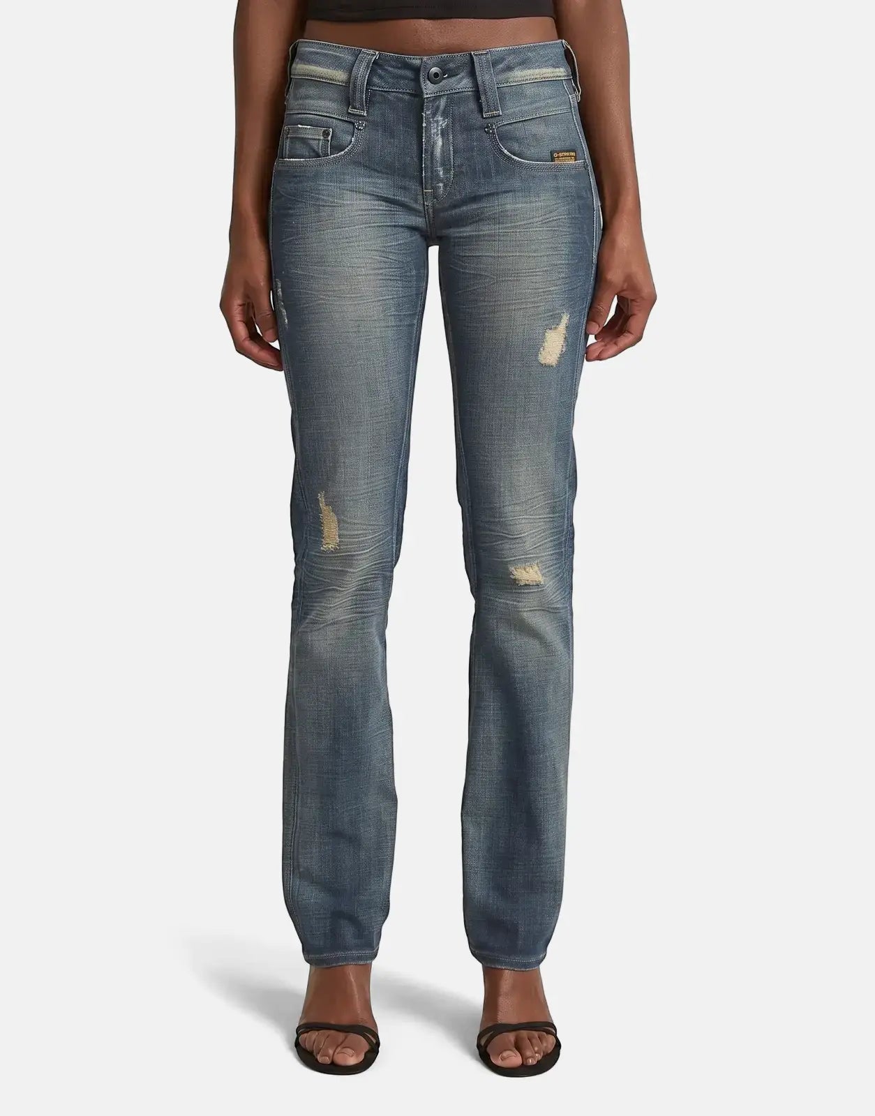 Full body view of a model wearing G-Star RAW Radar Slim Straight Vintage Desert Blue Jeans with distressed details and black